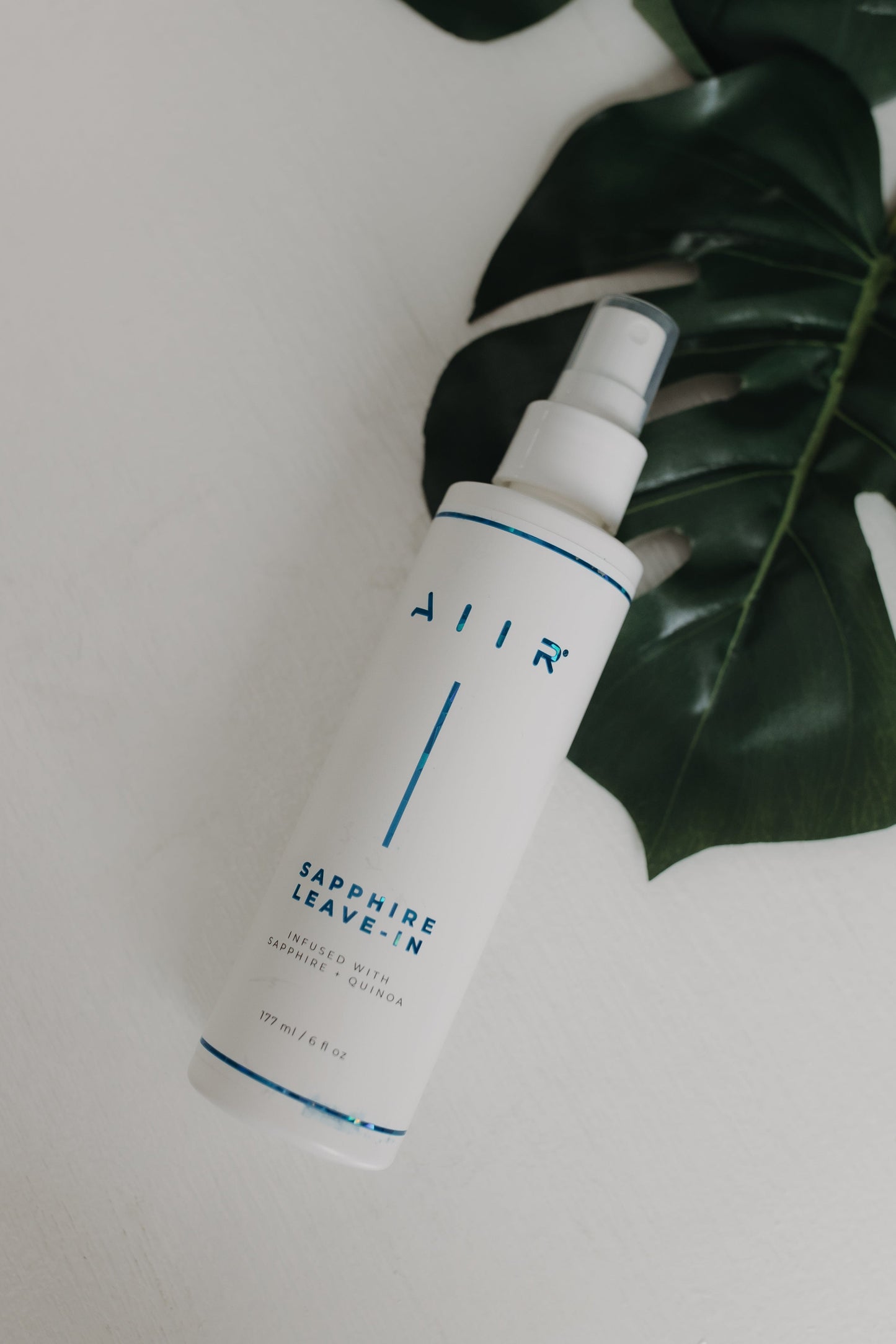 White spray bottle labeled 'AIR' with green leaves on a light background