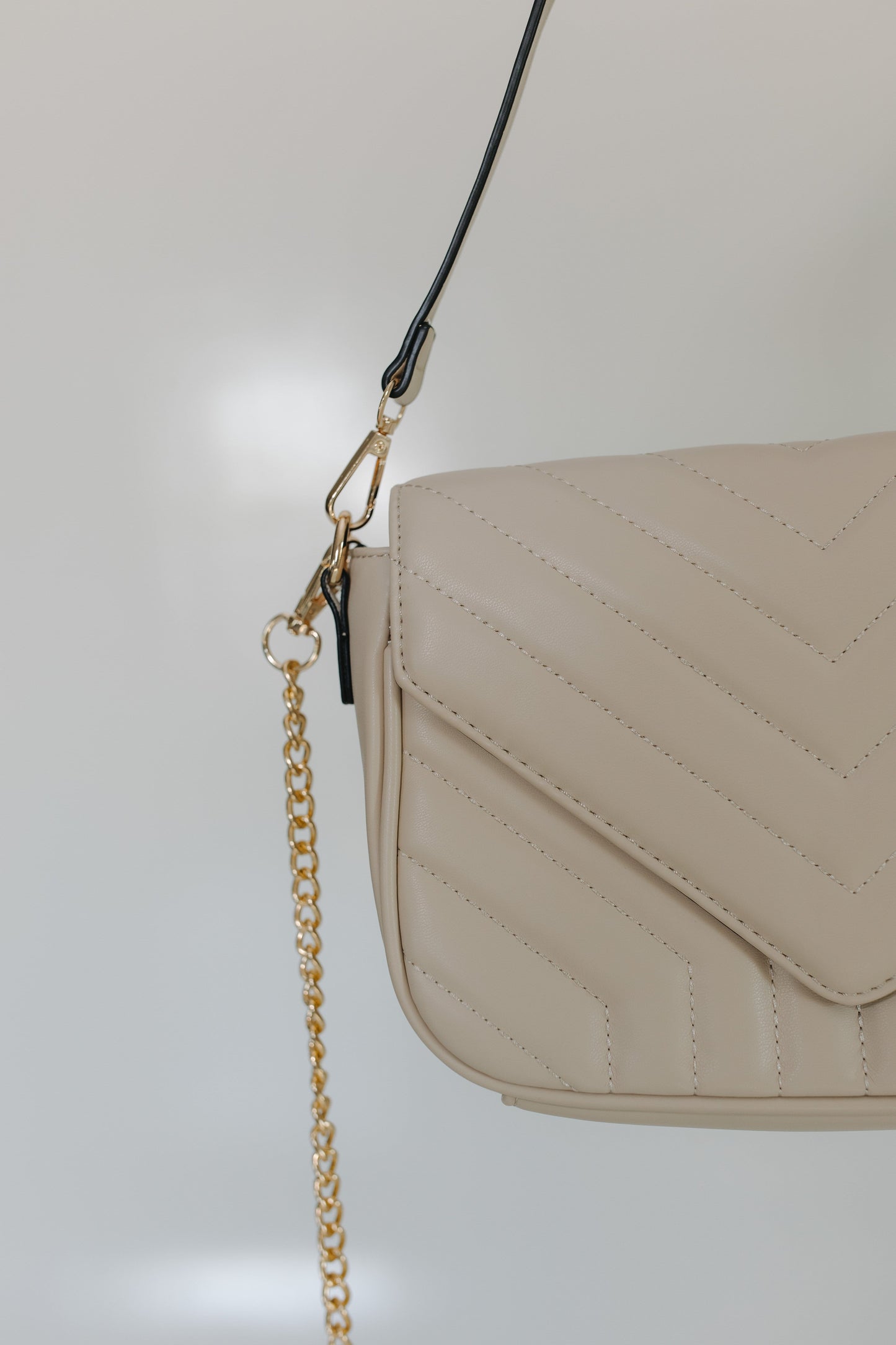 Beige handbag with a gold chain on a light gray background