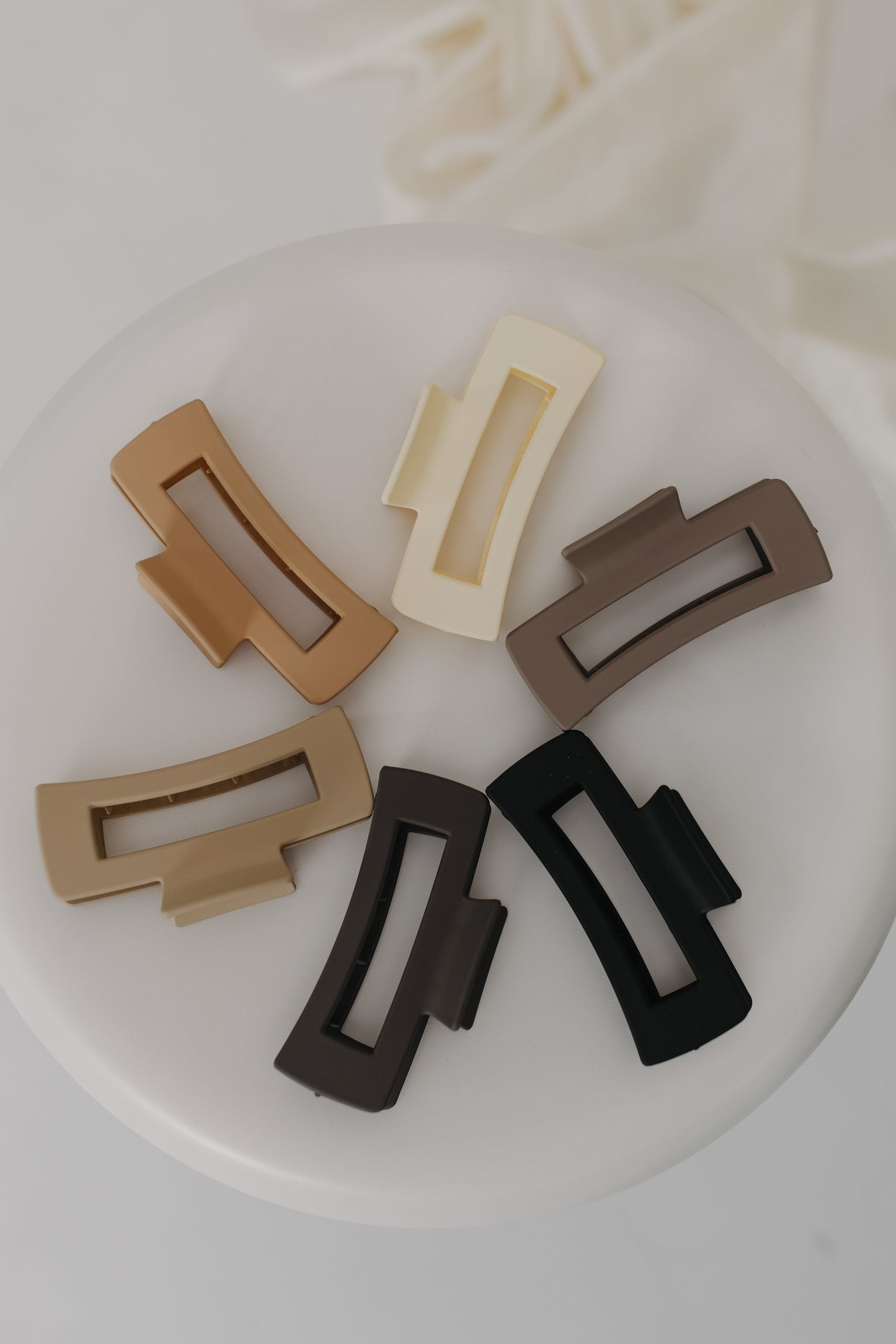 Set of six rectangular hair clip attachments in different colors on a white plate.