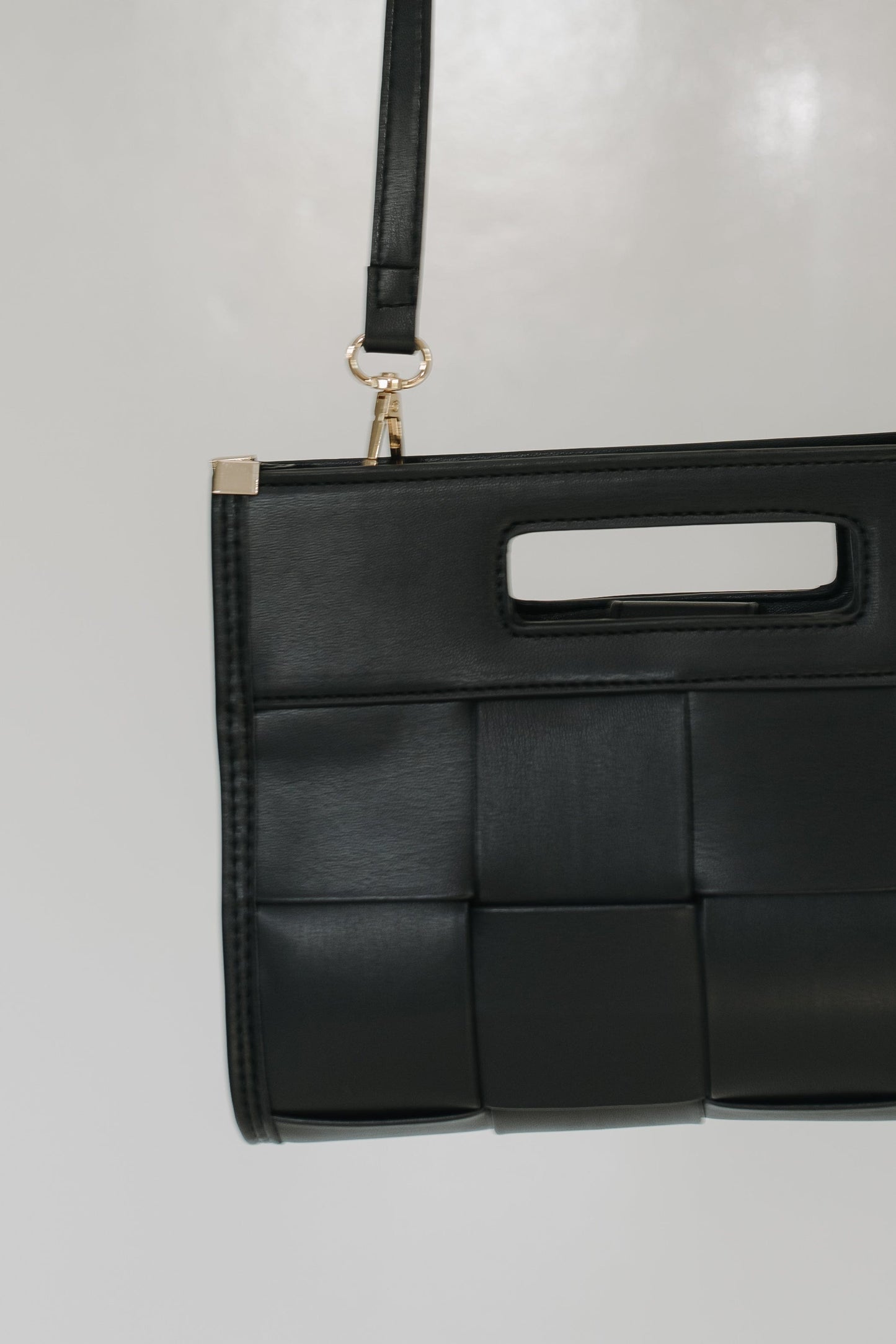 Black woven handbag on a light gray background