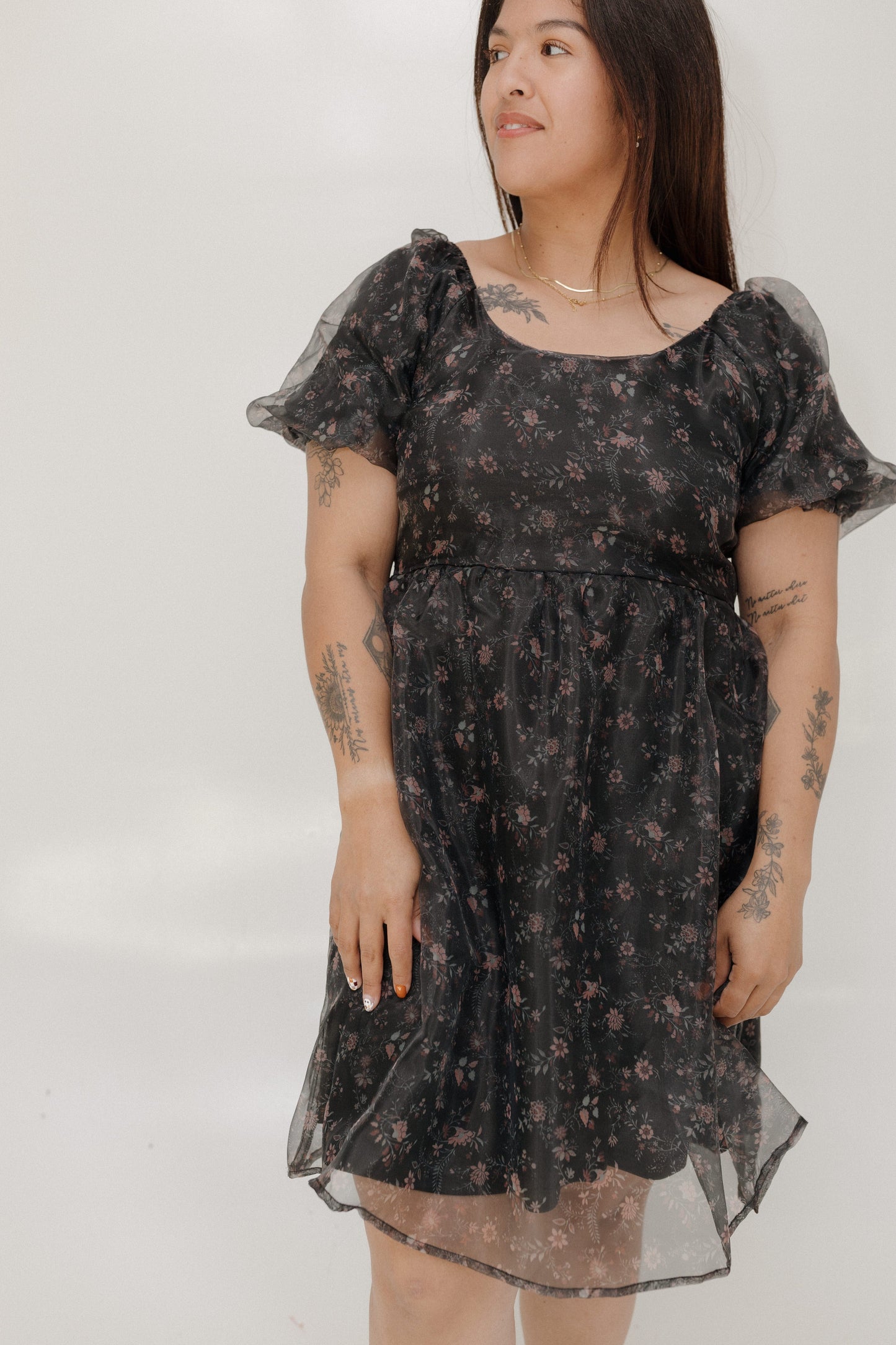 Woman wearing a black floral dress against a white background