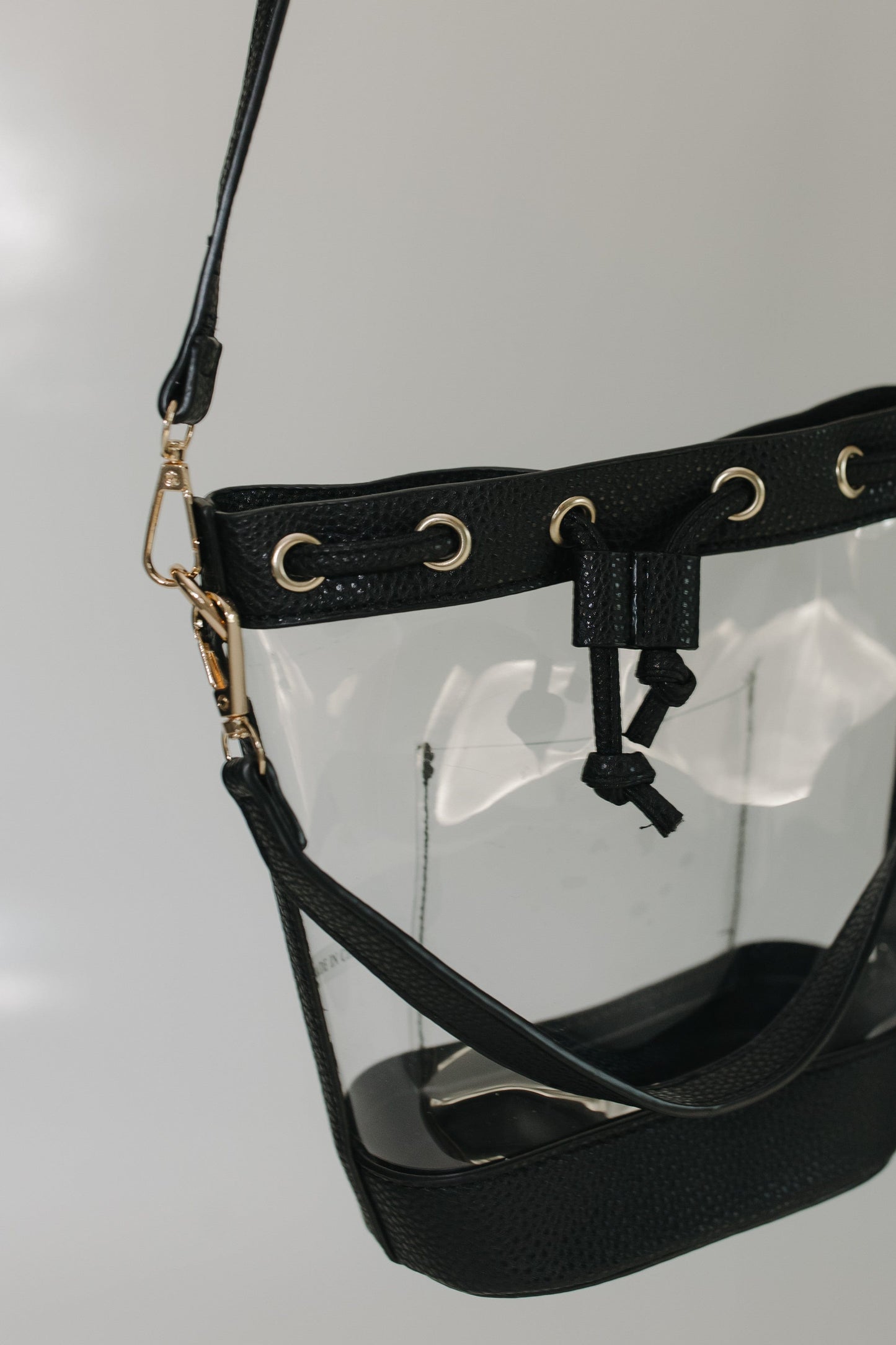 Black clear handbag with strap on a gray background