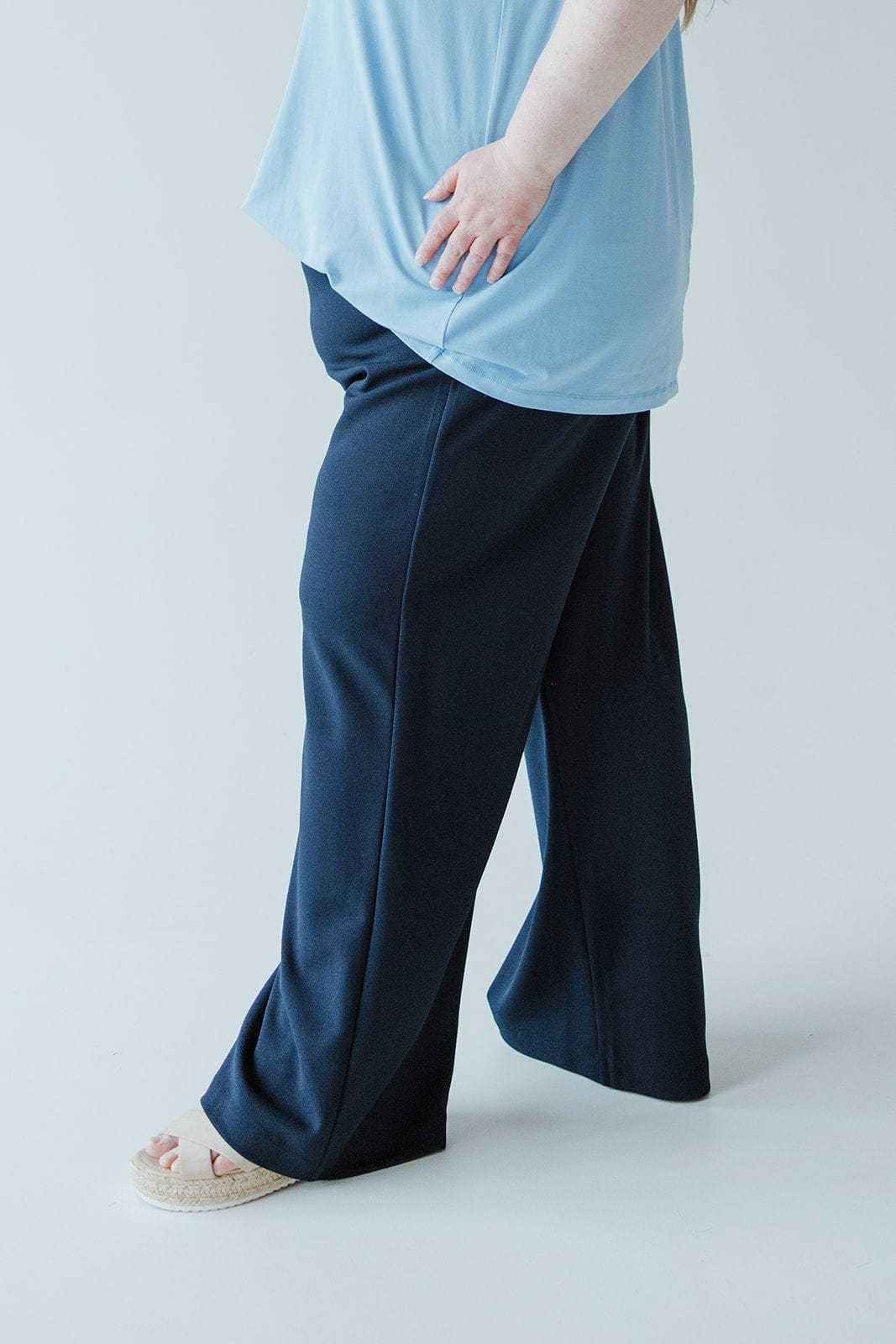 A person is wearing a light blue top and dark blue dress pants with wide legs, standing on a light background. The outfit features lightweight fabric that adds comfort and elegance to the look.
