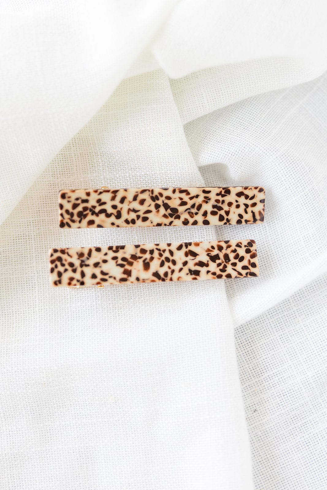 Introducing the Eleanor Hair Clips: two rectangular, quirky clips with a leopard print pattern on a white fabric background, crafted from plant-based acrylic.