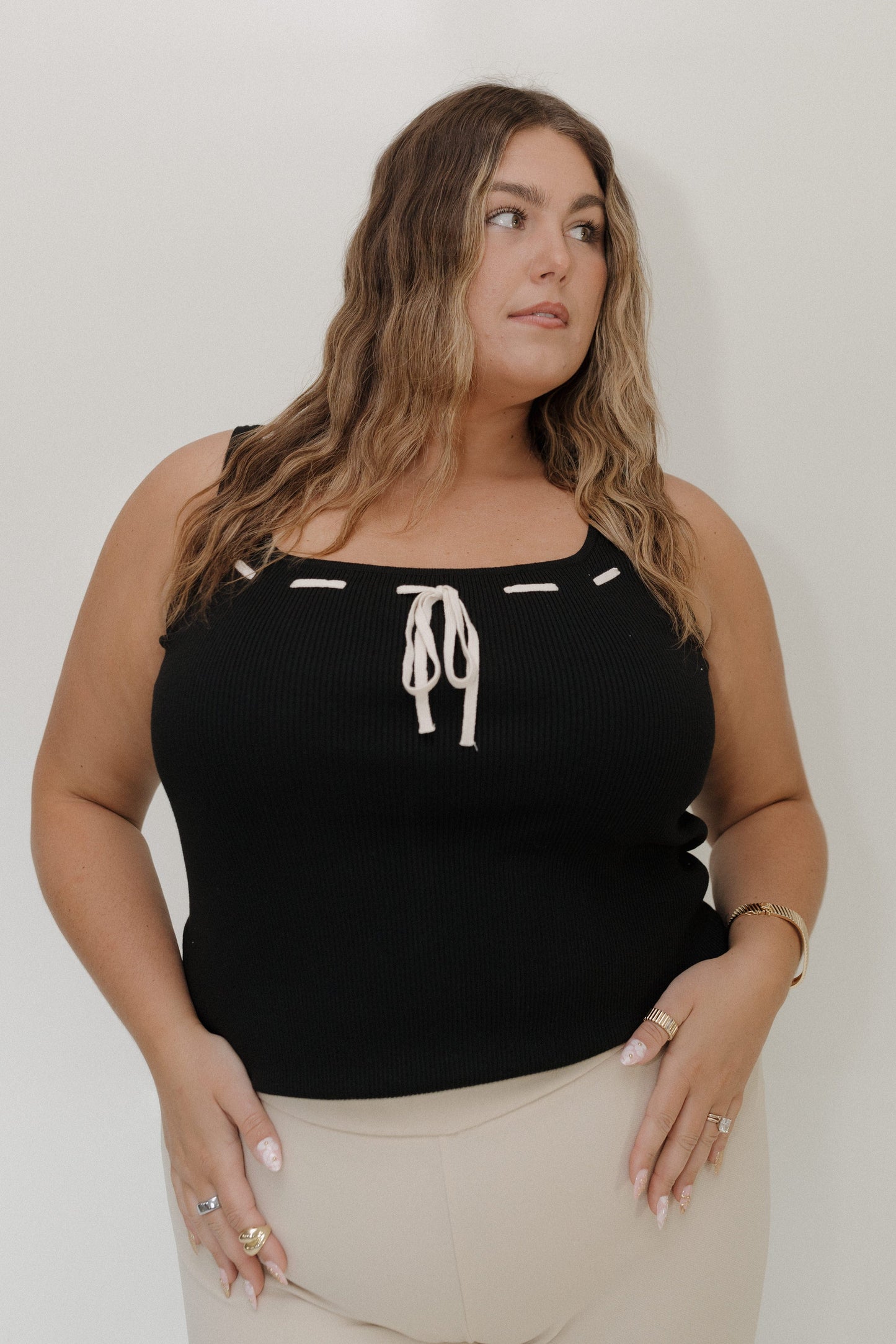 Woman wearing a black tank top with white accents against a plain background