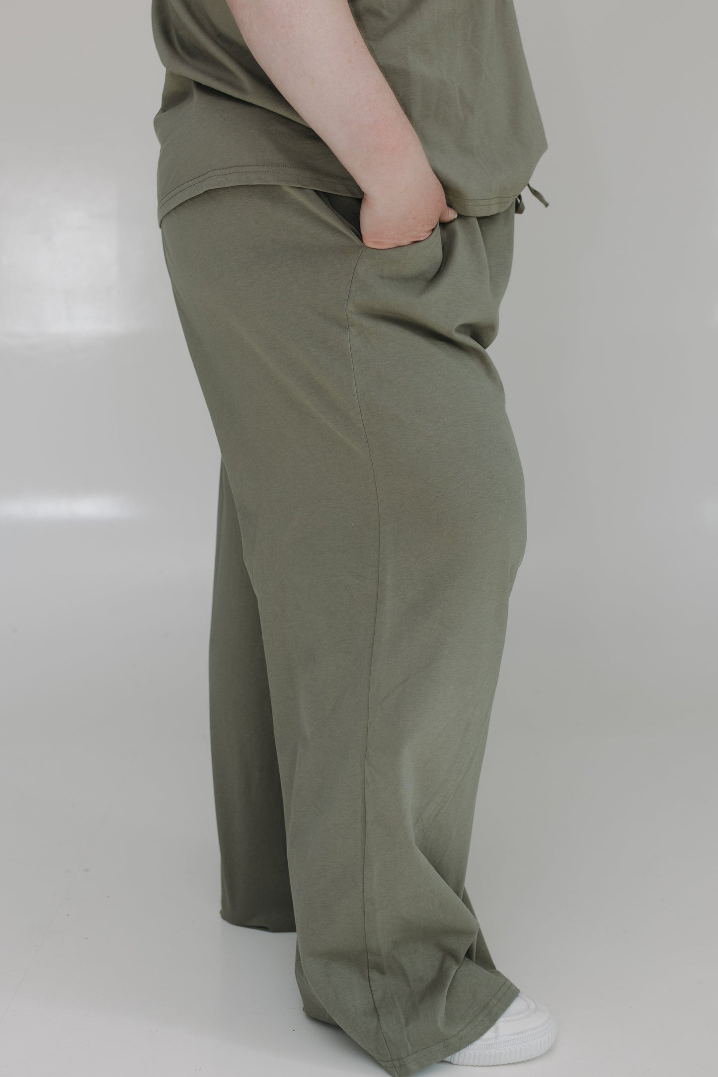 Person wearing olive green pants on a white background