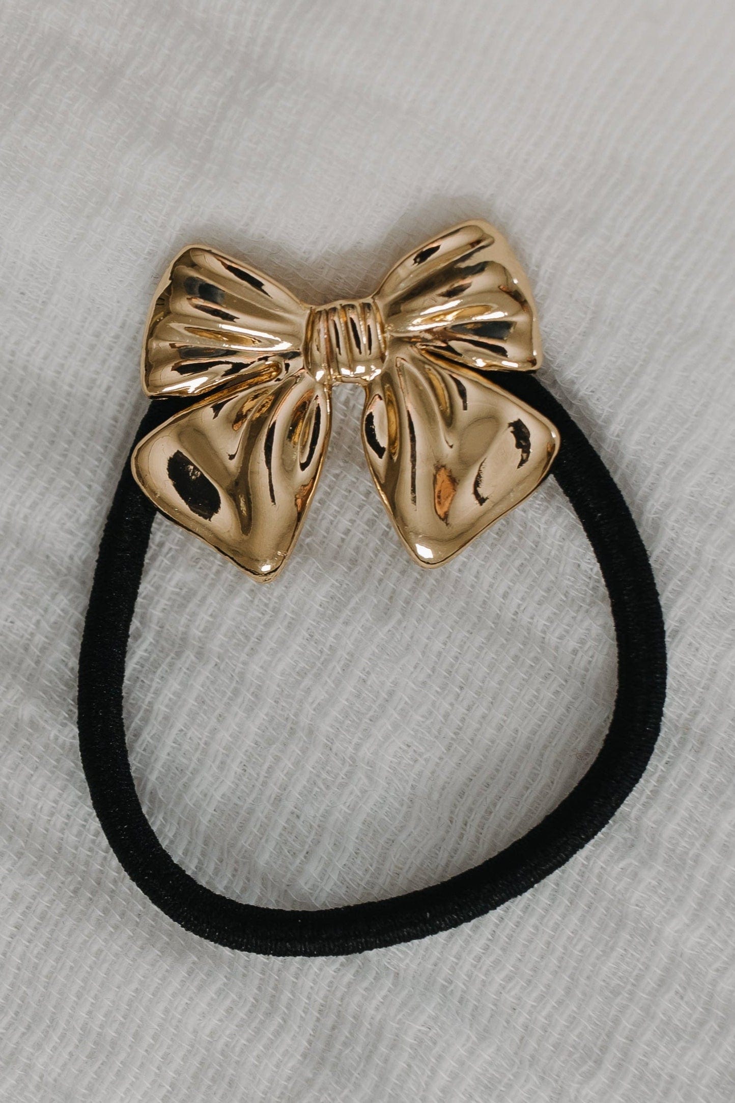 Gold bow hair tie on a gray background