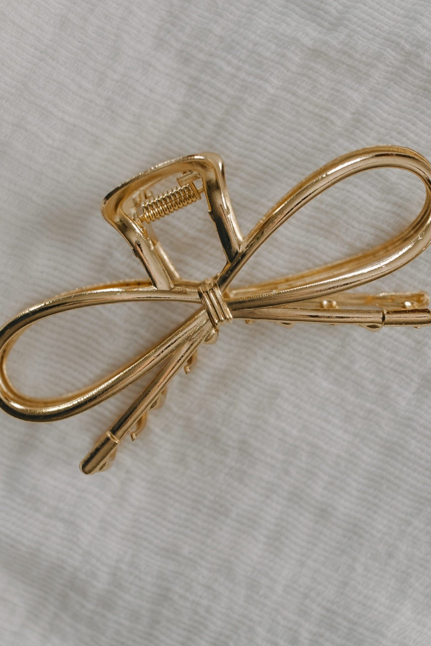 Gold bow-shaped hair clip on a light gray background