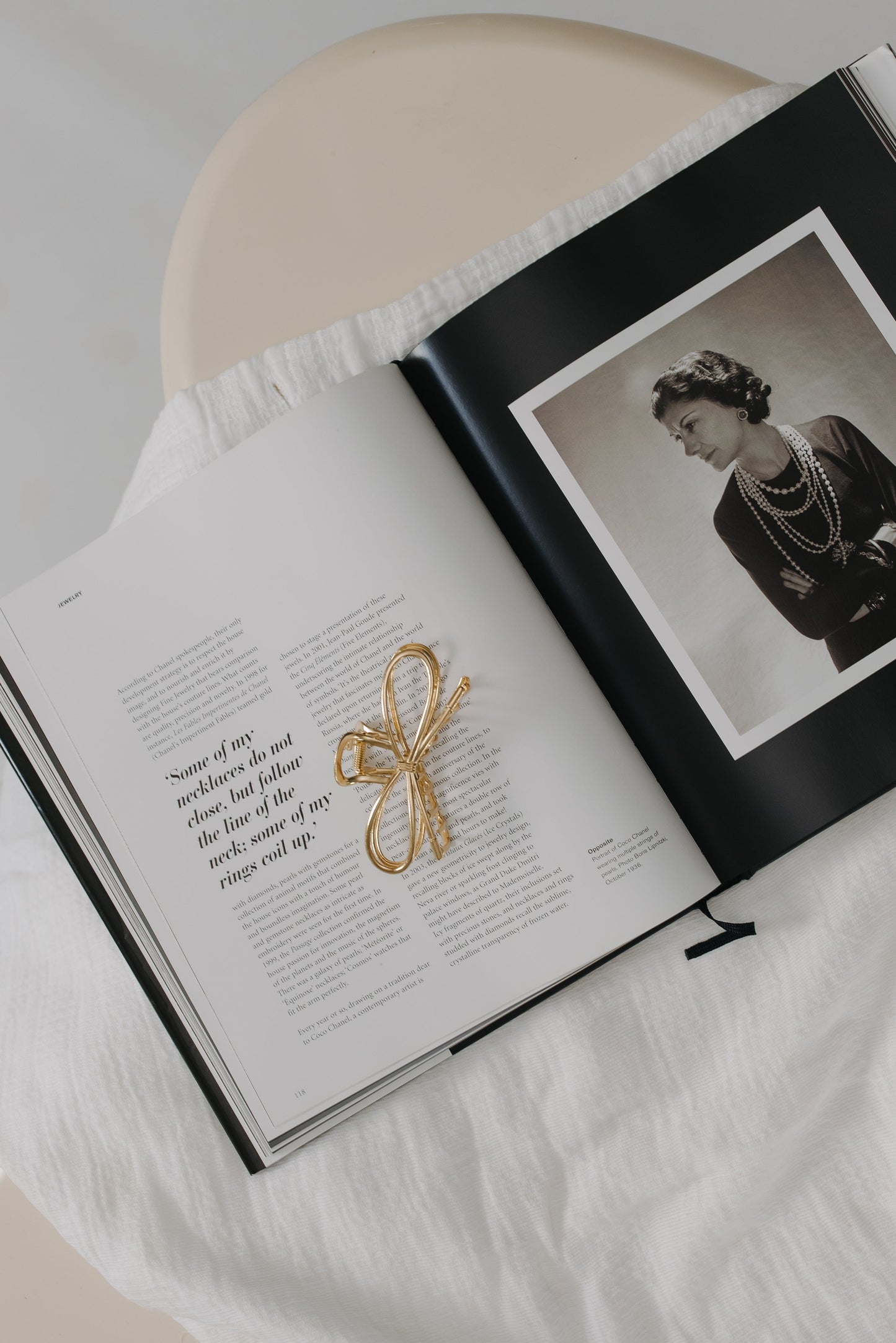 Open book with a photograph of a woman and a gold bow on a white surface