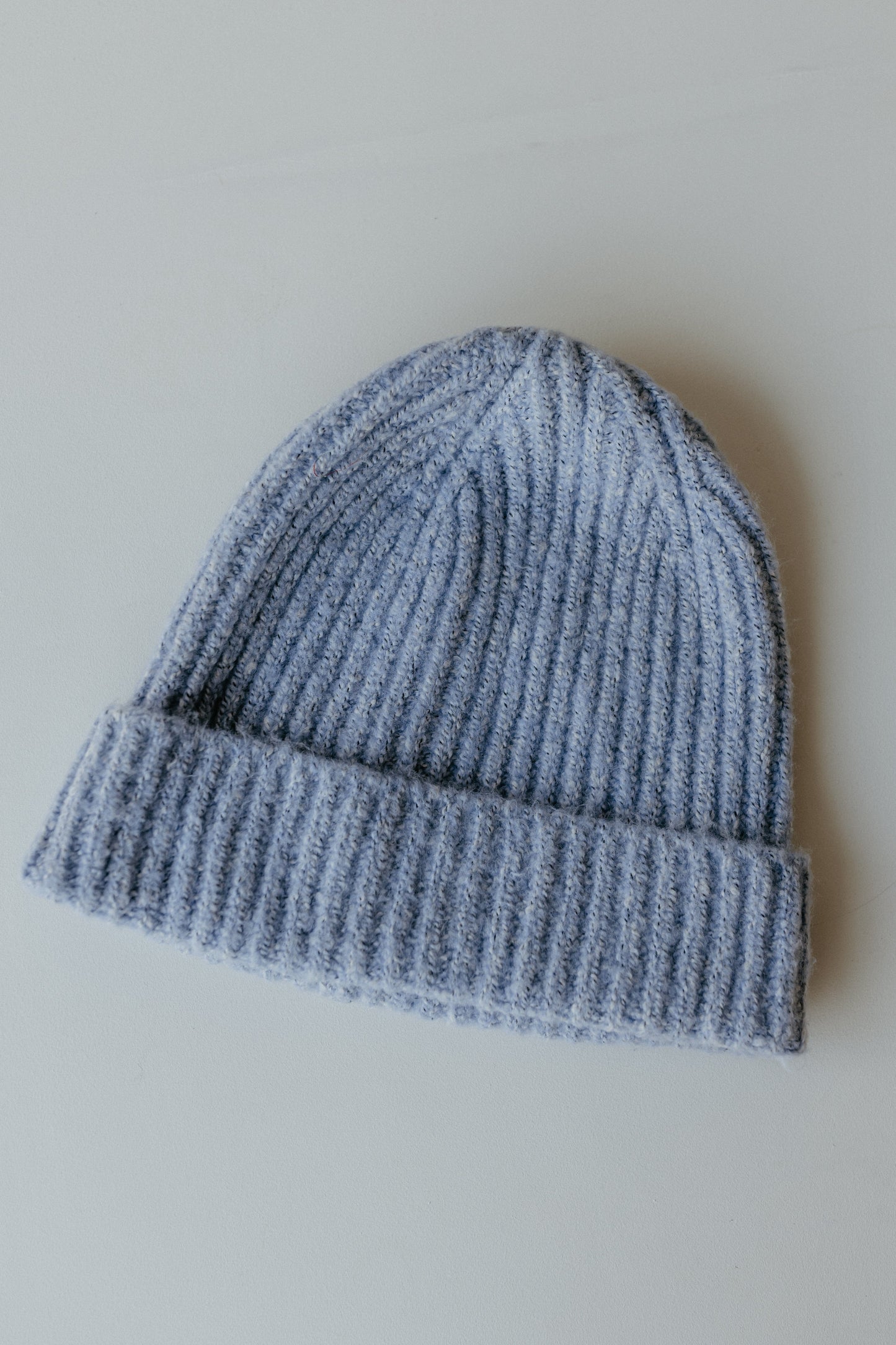 A cozy gray knit stocking hat with a folded brim lies on a plain surface, perfect for autumn days. Made from 100% acrylic, it adds warmth and style to your fall accessories collection.