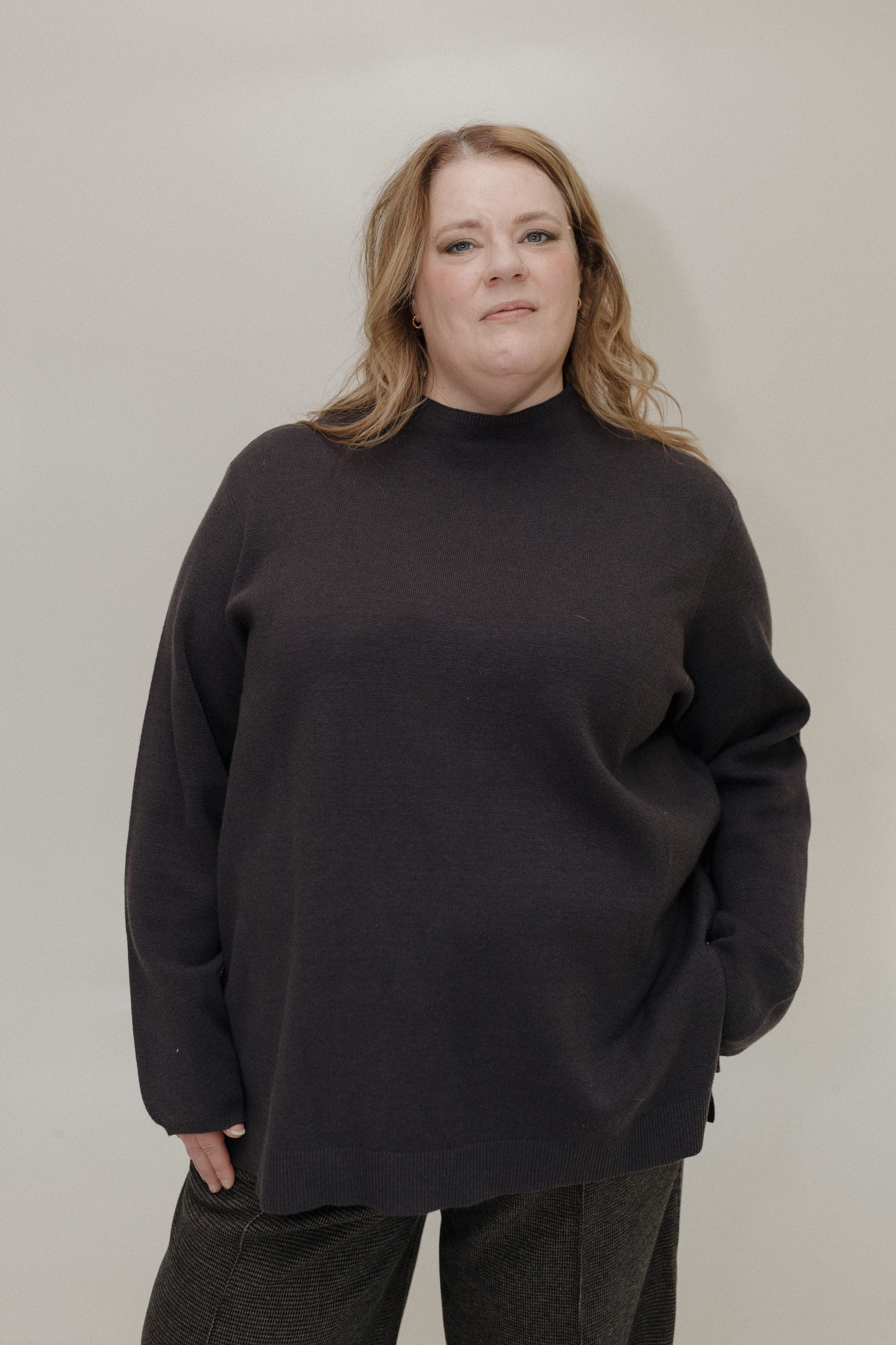Person wearing a black sweater against a plain background