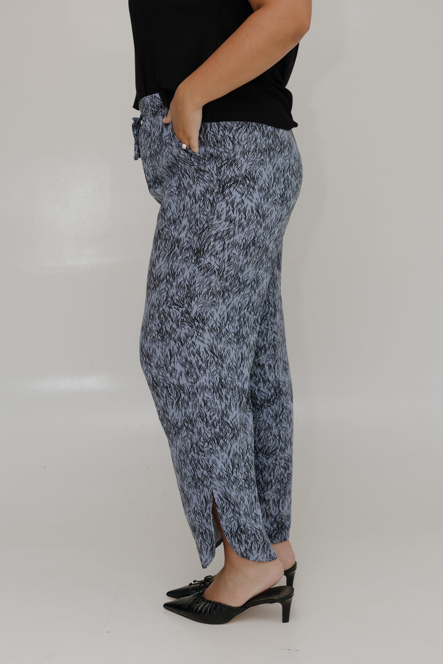 Person wearing a patterned skirt and black top on a plain background