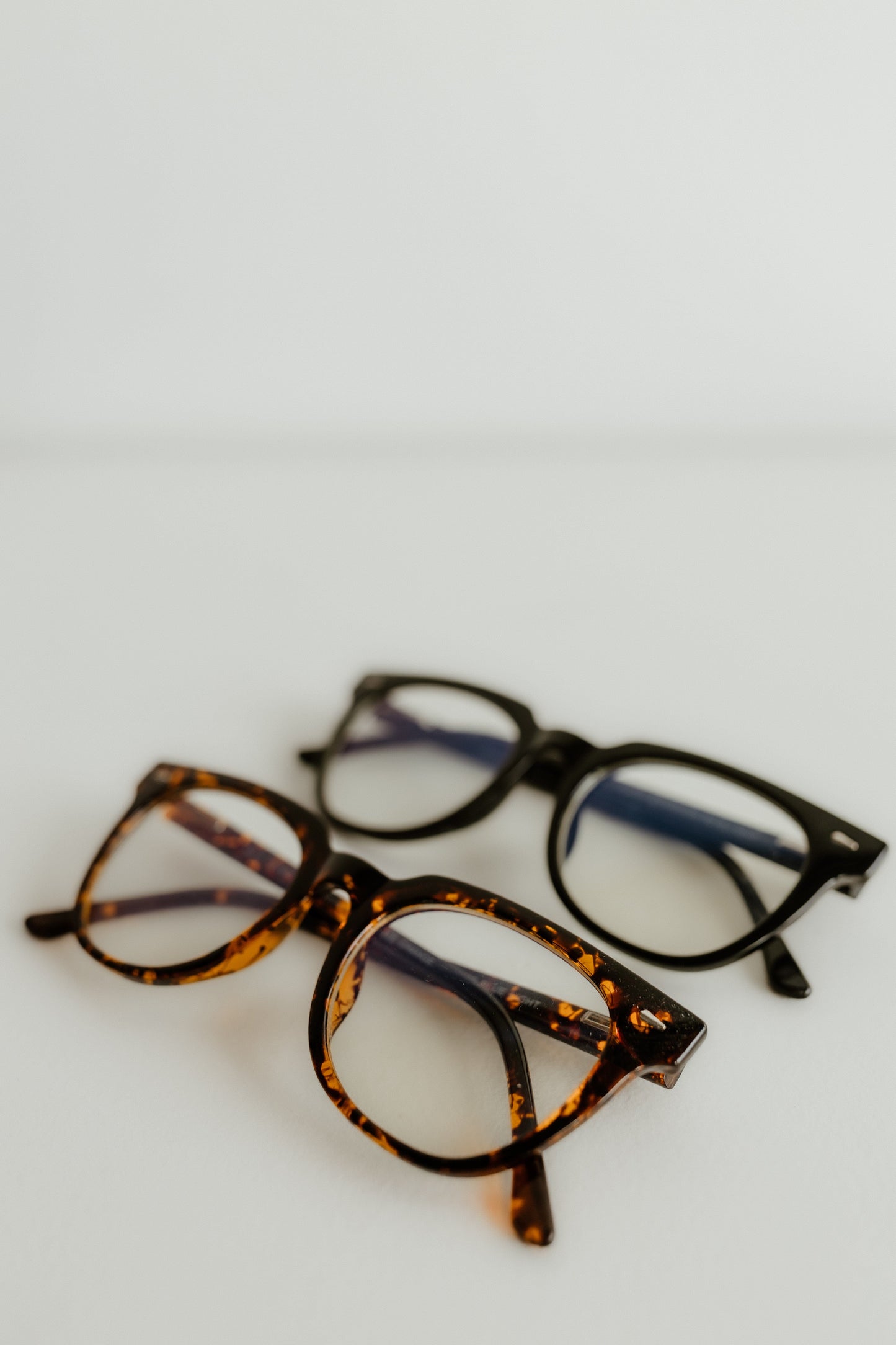 Three pairs of eyeglasses with different frames on a light gray background