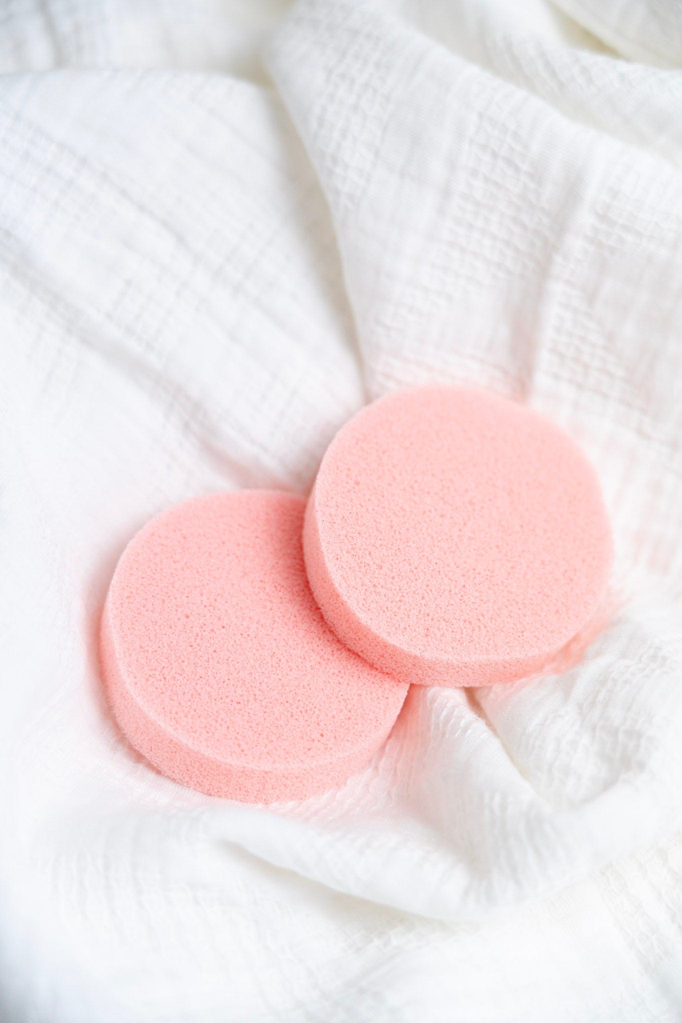 Two pink deodorant removers on a white textured fabric background