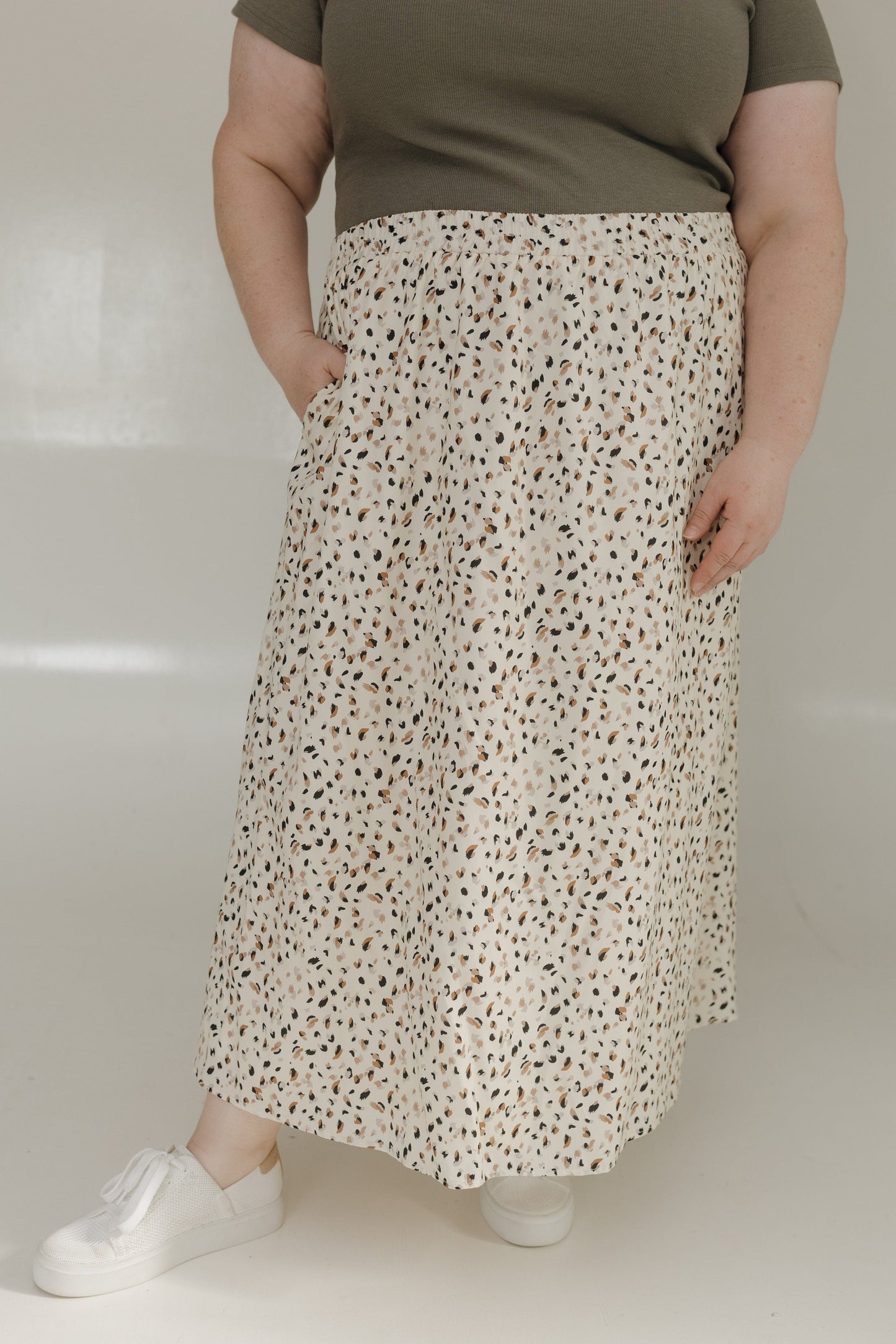 Person wearing a floral skirt and green top on a plain background