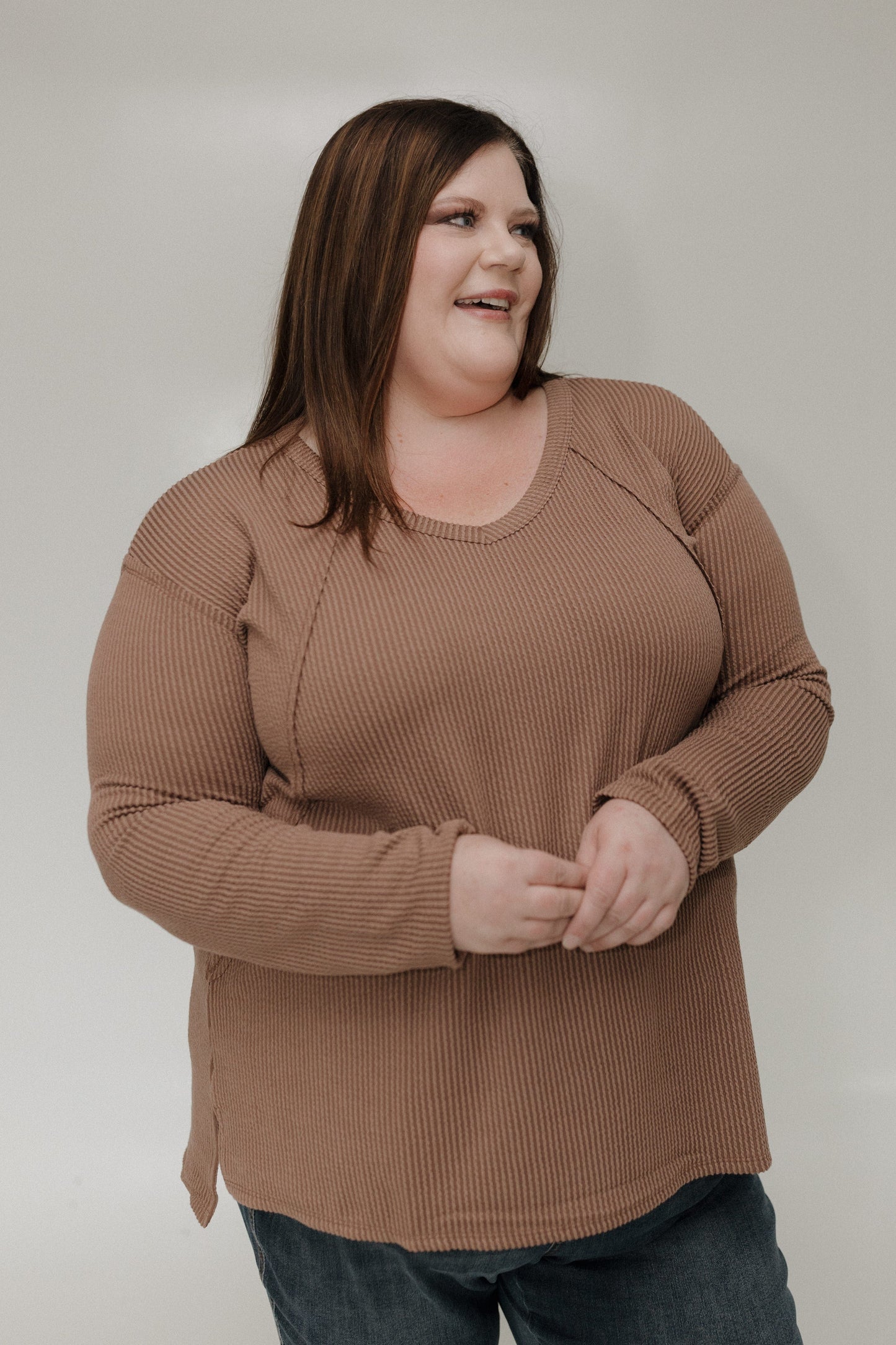 Woman wearing a brown tee against a plain background