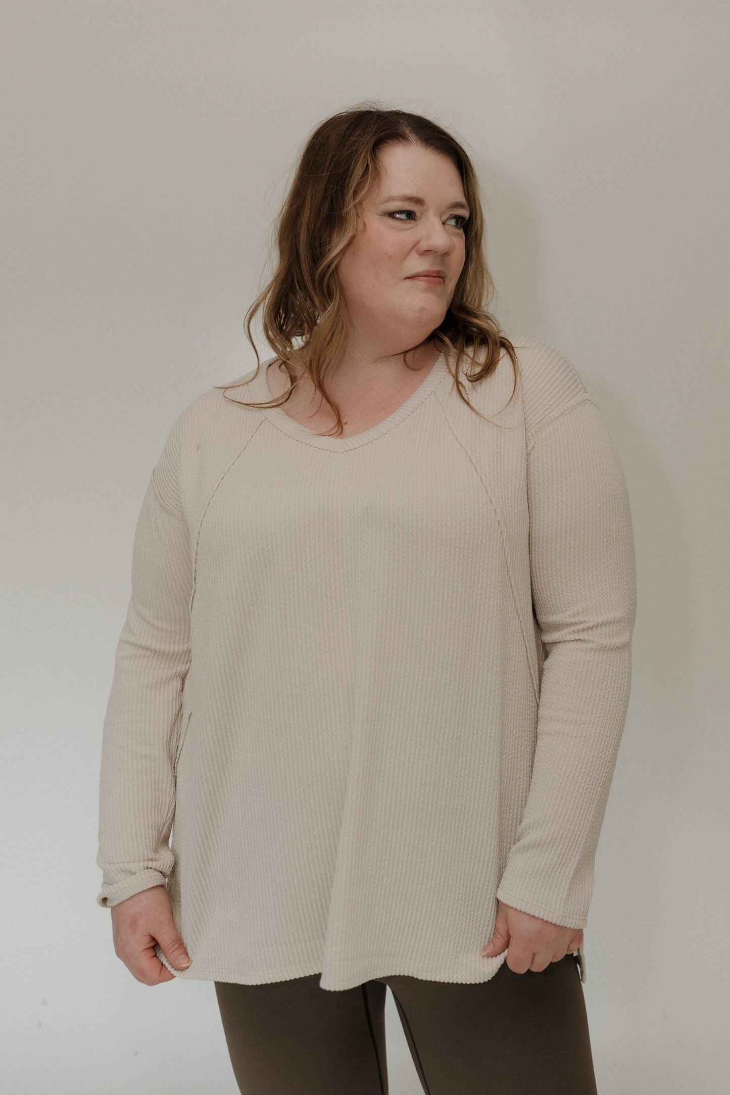 Woman wearing a sand shirt against a plain background