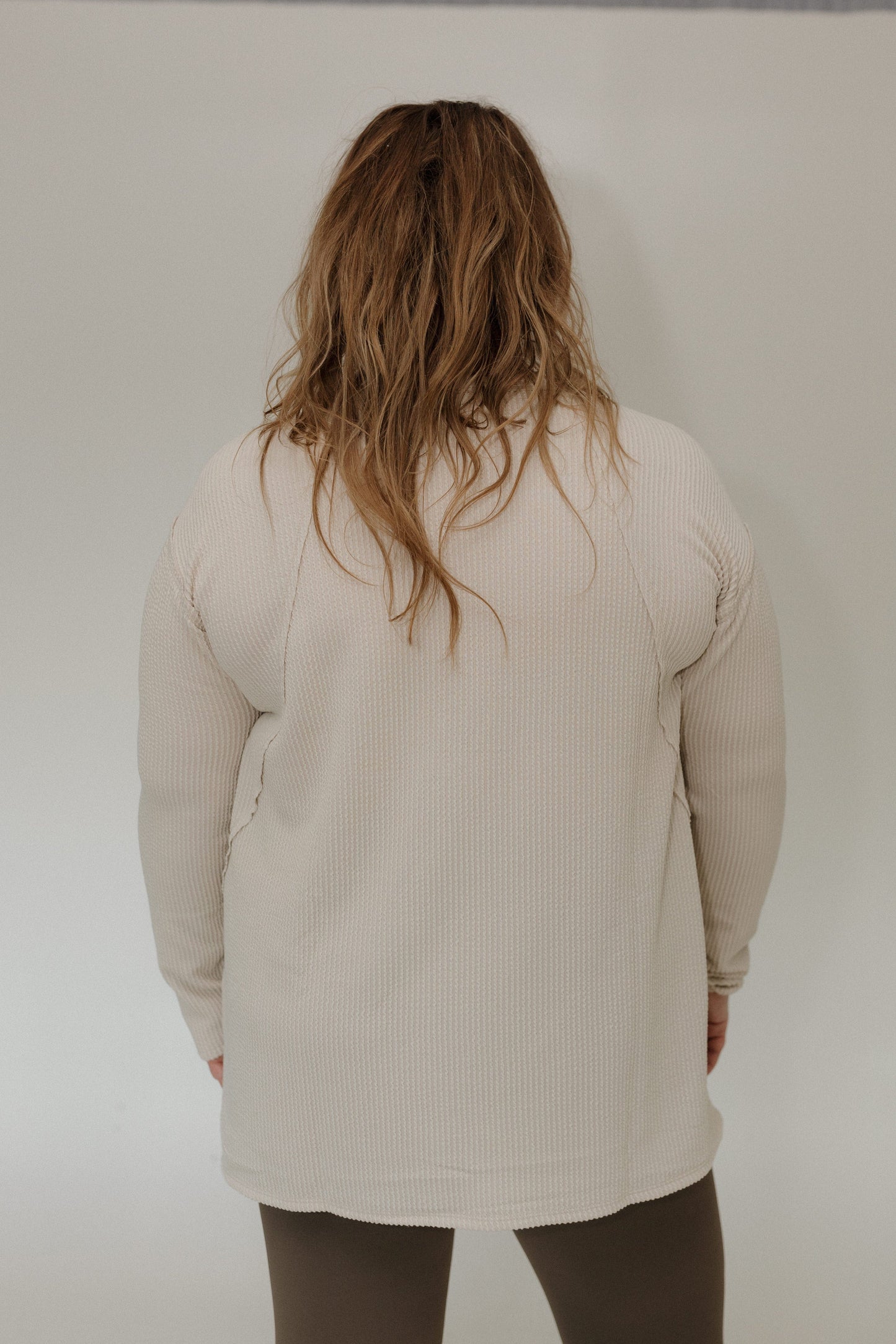 Person wearing a sand ribbed shirt against a plain background