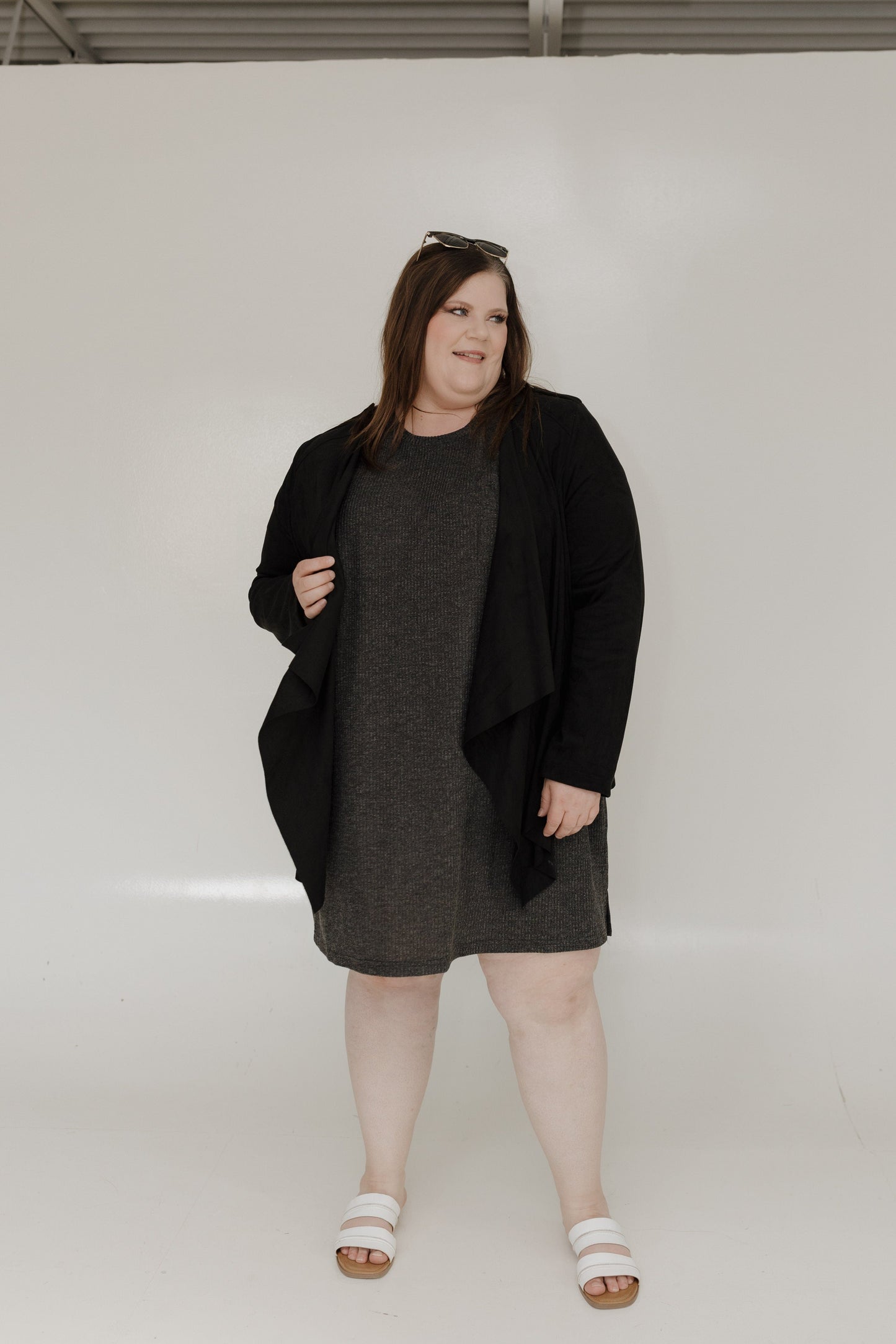 Woman wearing a black coat over a gray dress on a white background