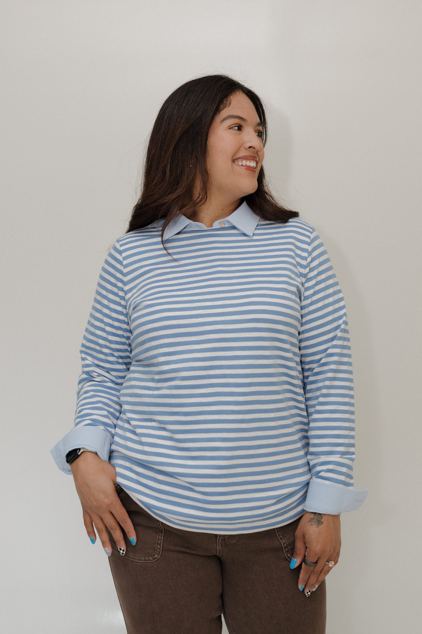 Woman wearing a blue and white striped shirt against a plain background
