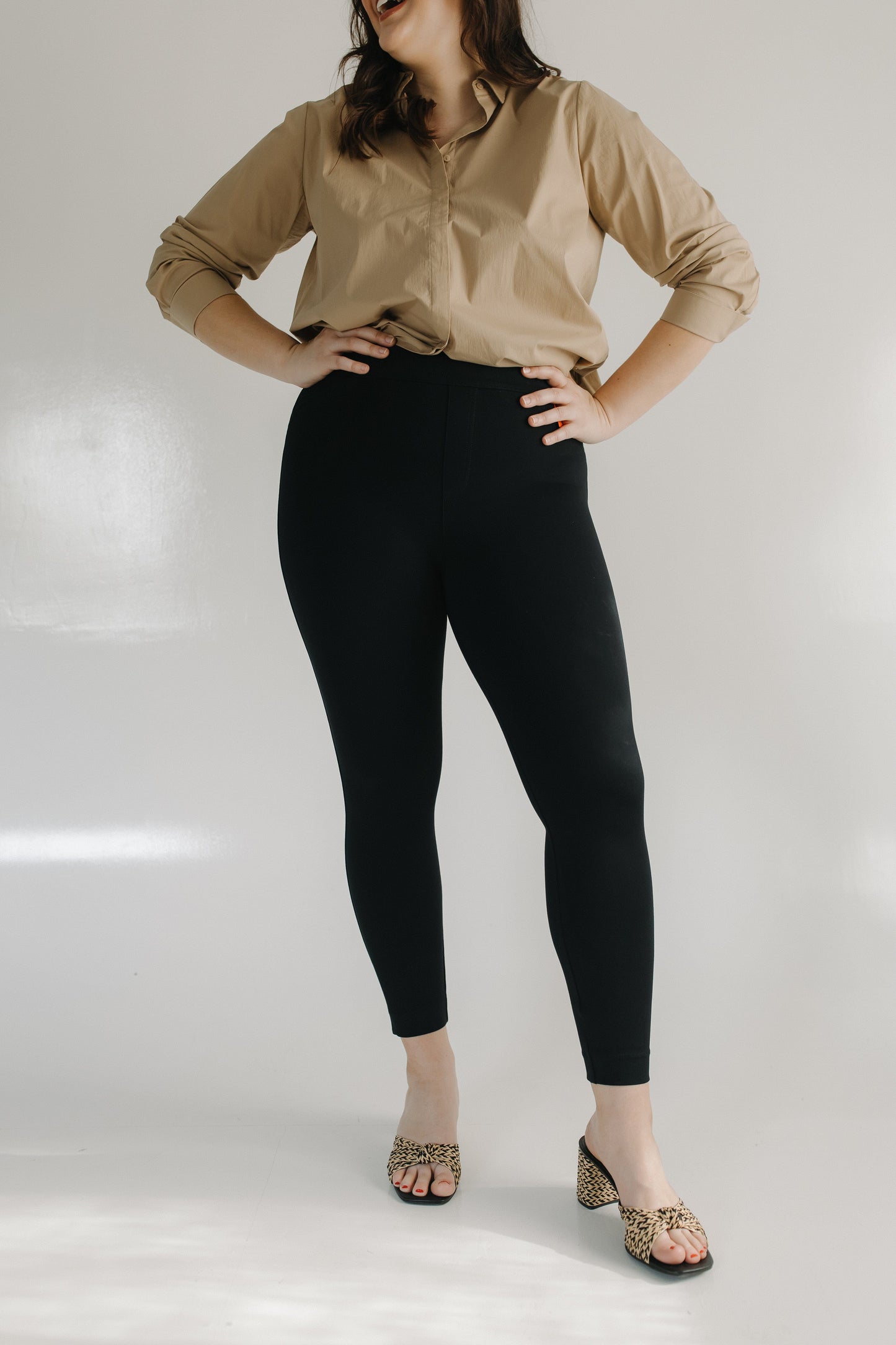 Woman wearing a beige blouse and black pants on a white background