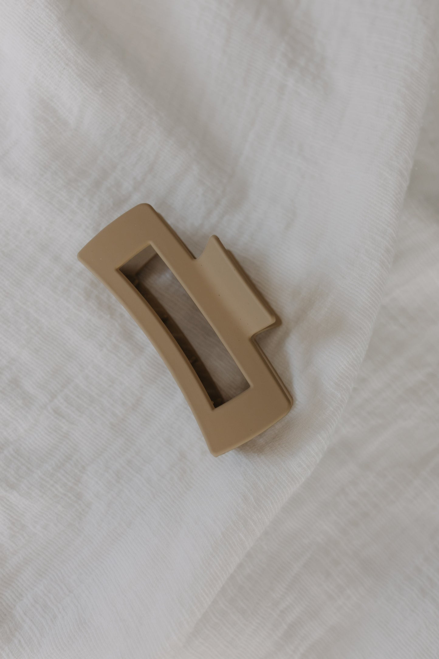 Warm Sand claw clip on a white fabric background