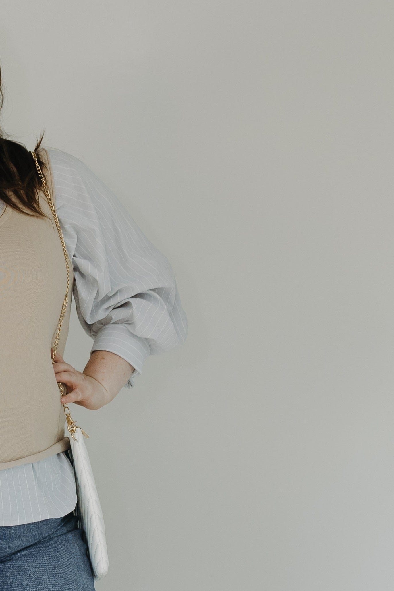 Person holding a white clutch against a plain background