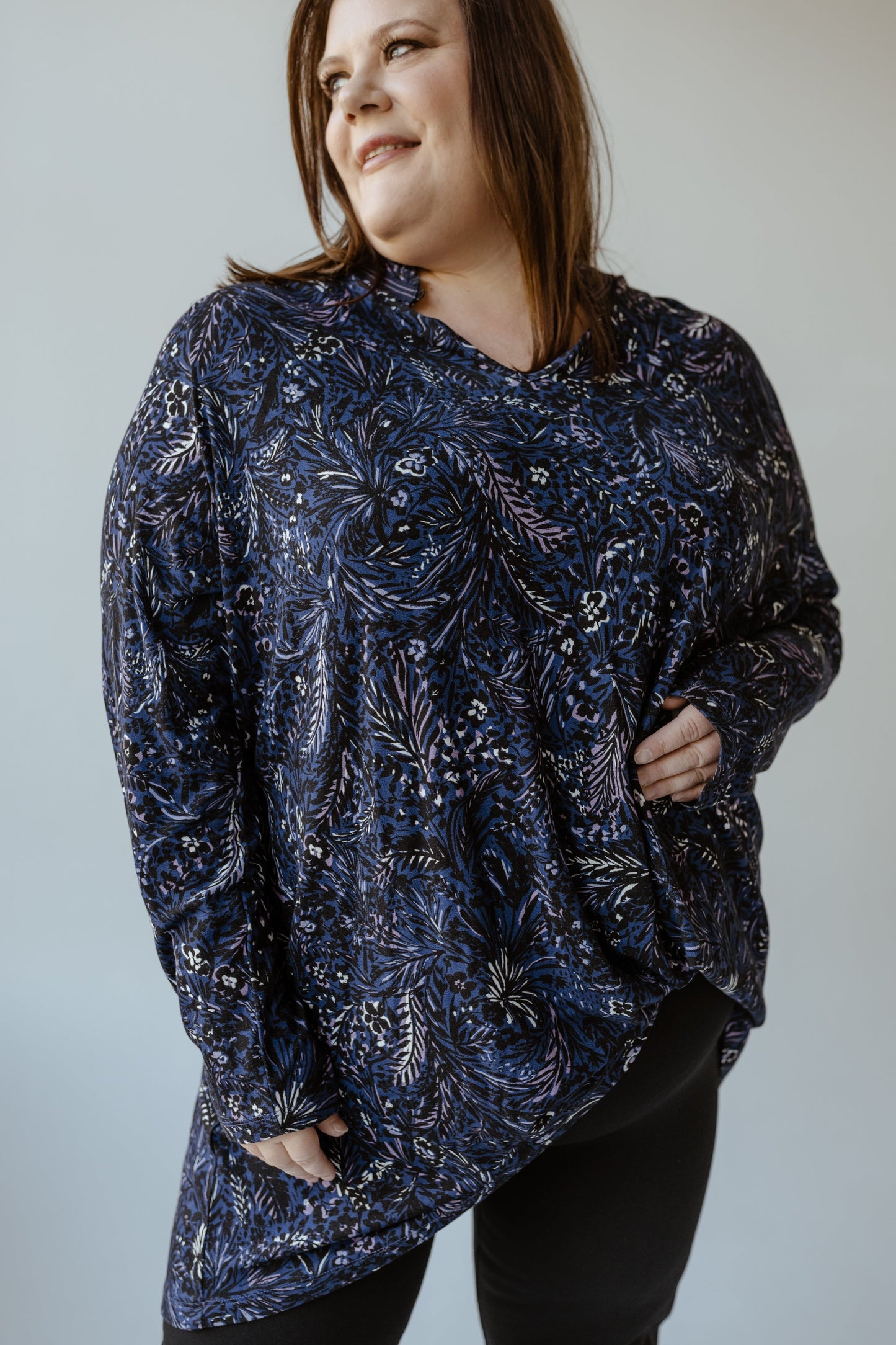 A person smiling and looking to the side, wearing a Yesta Abstract Floral Turtleneck Blouse paired with black pants.