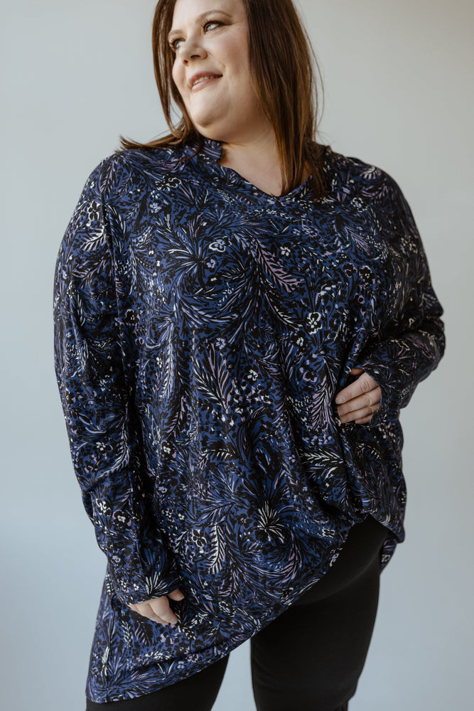 A person wearing a figure-flattering Abstract Floral Turtleneck Blouse by Yesta and black pants stands facing away against a neutral background.