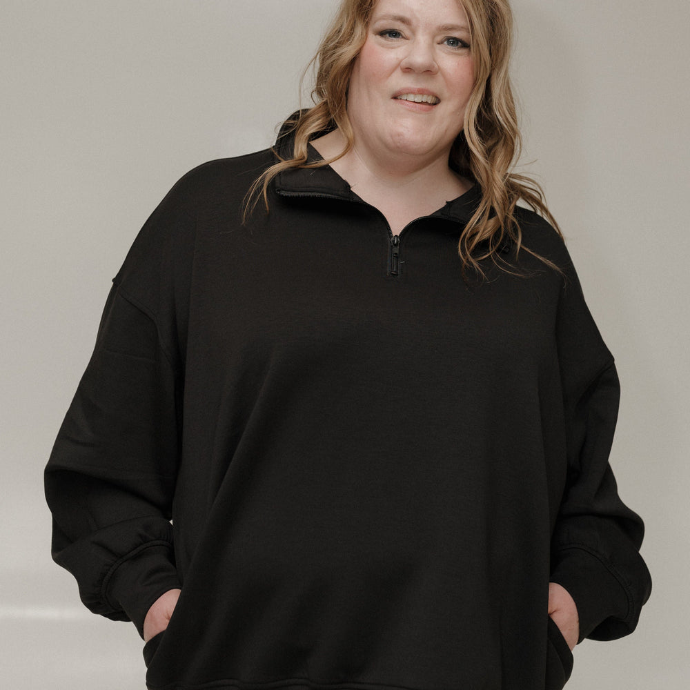 Person wearing a black sweater against a plain background