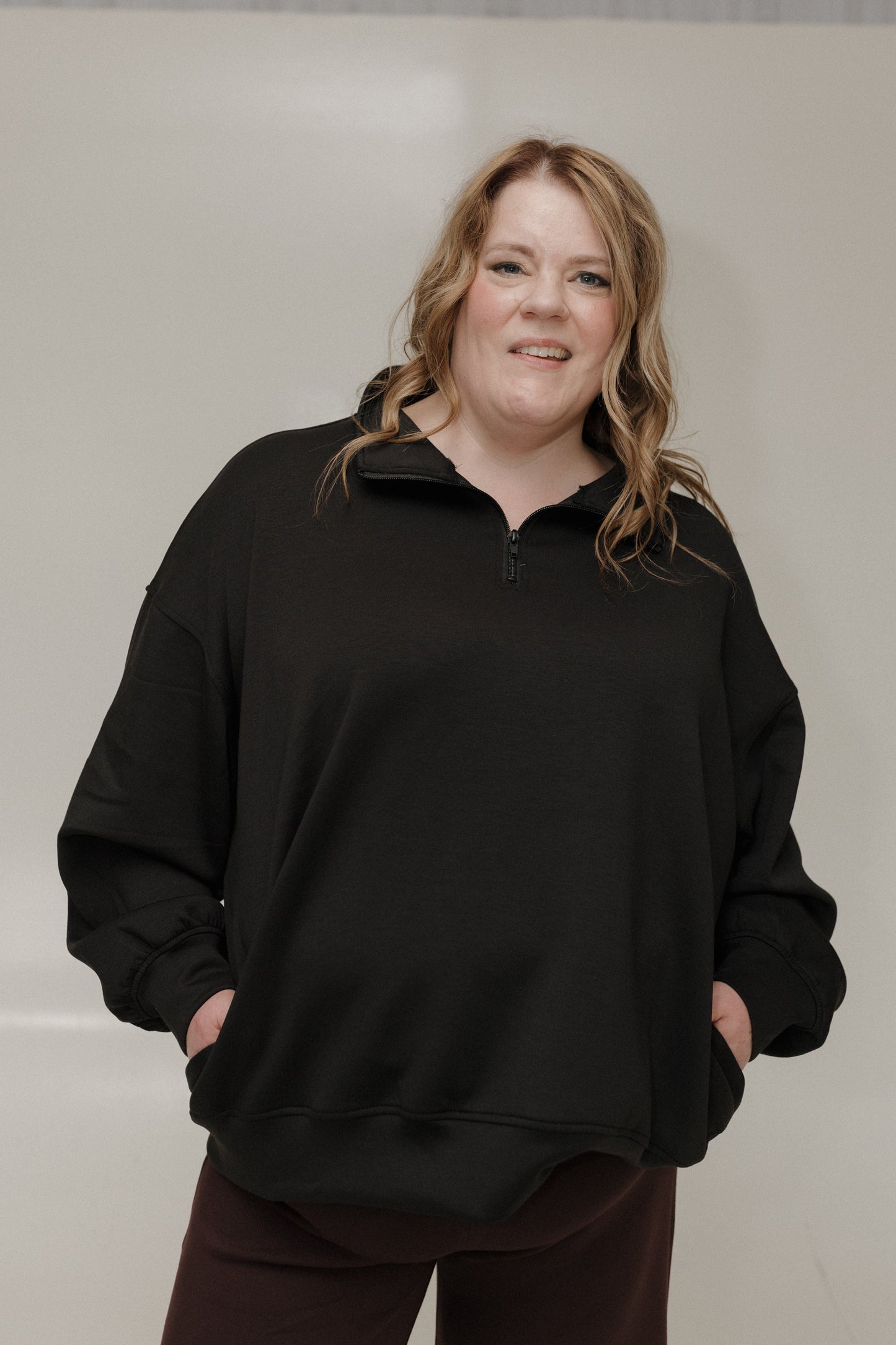 Person wearing a black sweater against a plain background