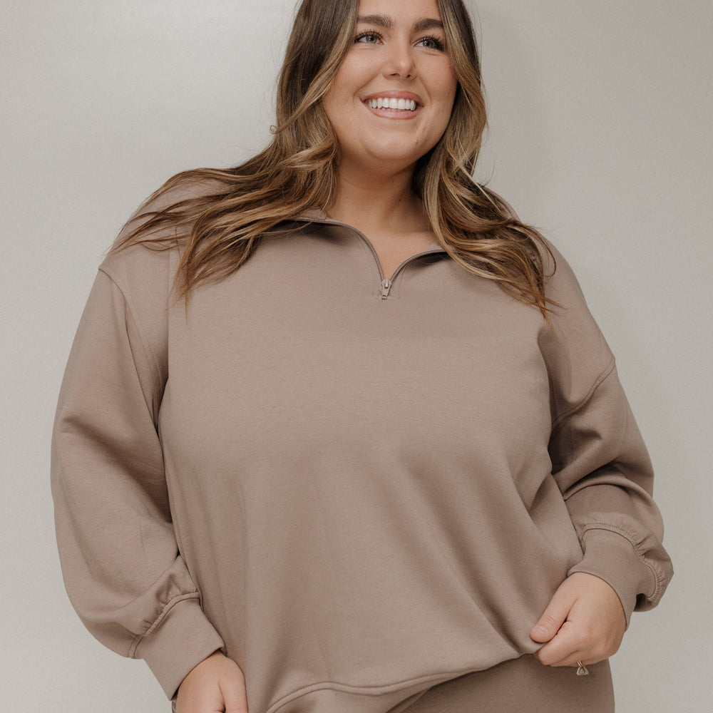 Woman wearing a beige lounge set against a plain background