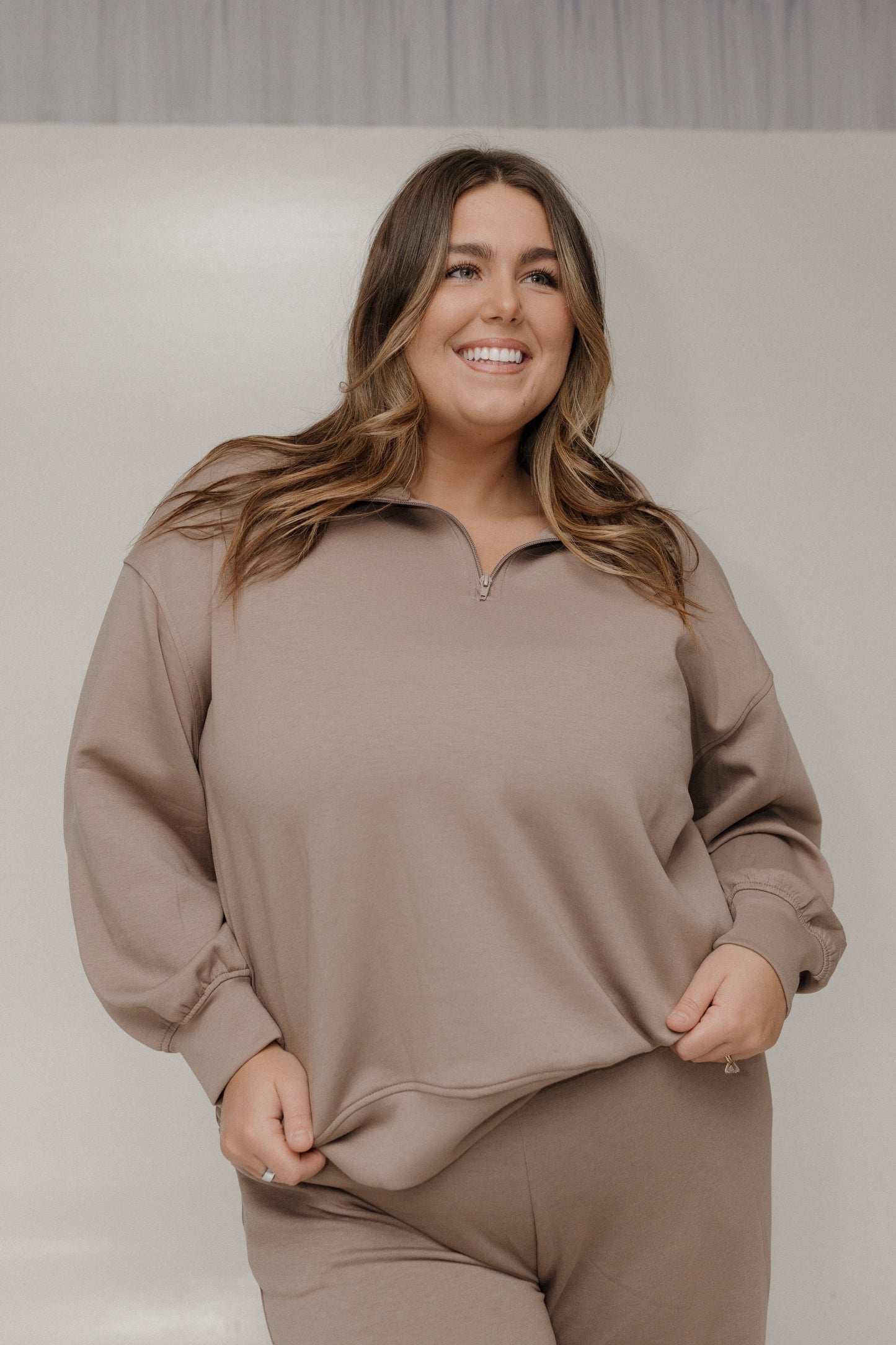 Woman wearing a beige lounge set against a plain background