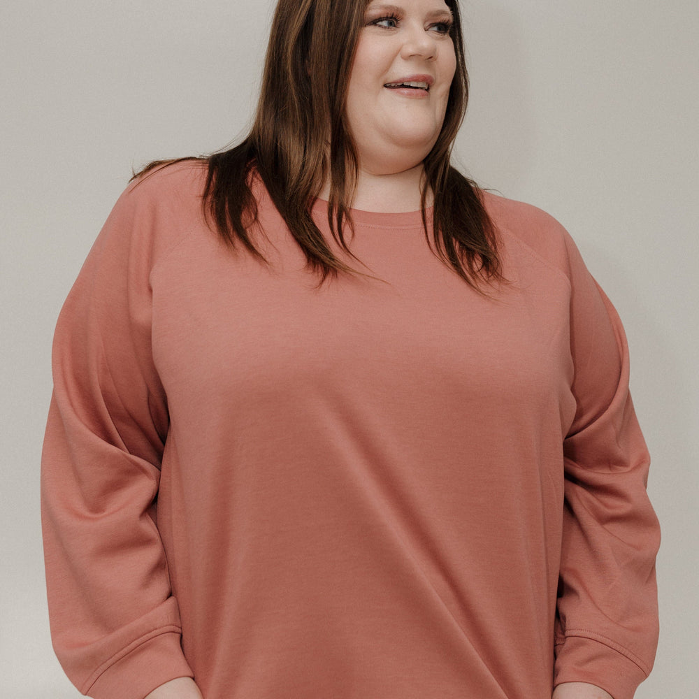 Woman wearing a pink sweatshirt against a plain background
