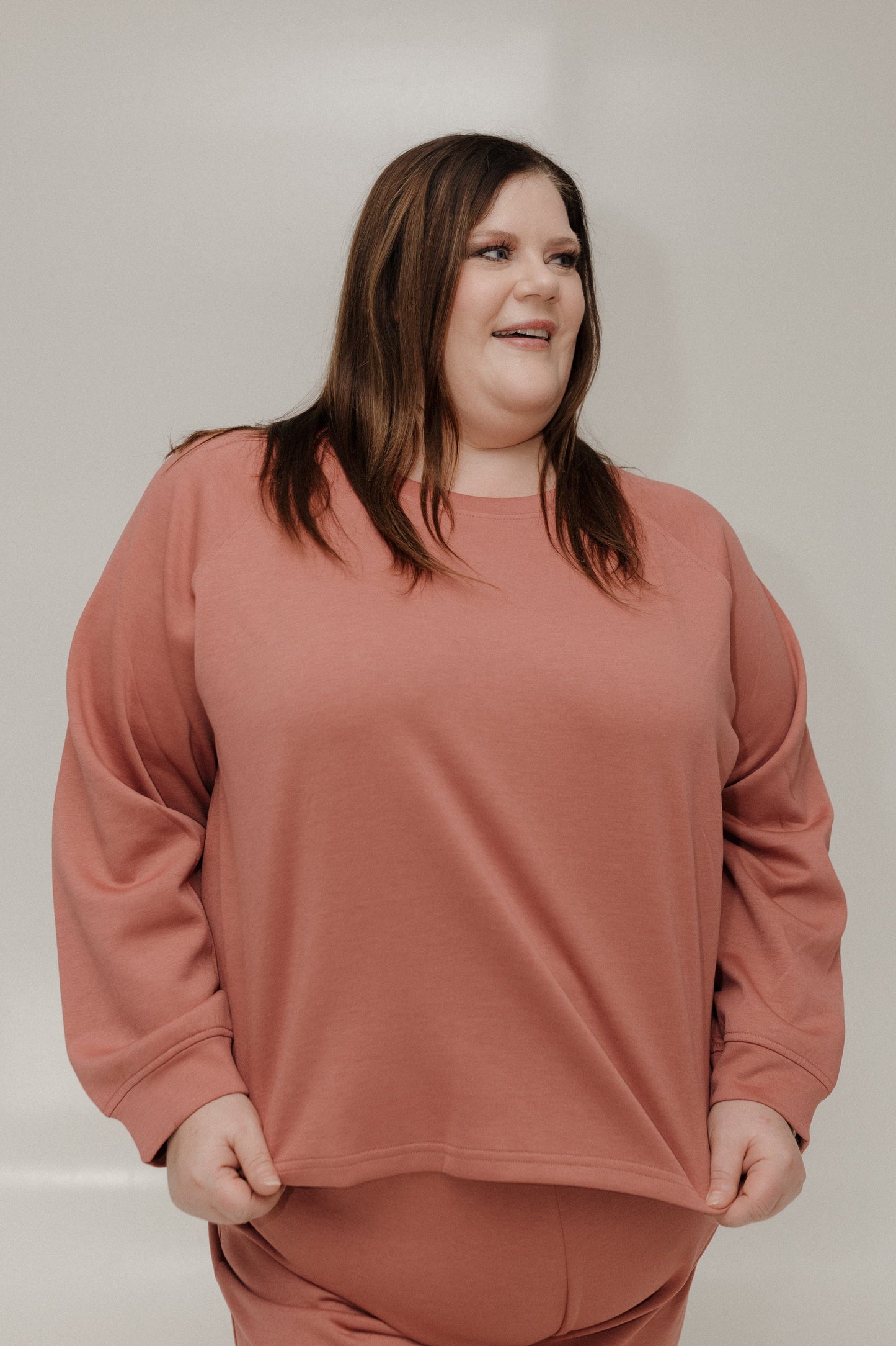 Woman wearing a pink sweatshirt against a plain background
