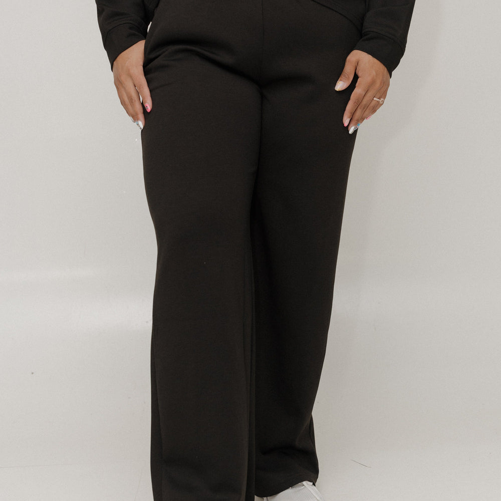 Person wearing a black outfit with wide-leg pants on a white background