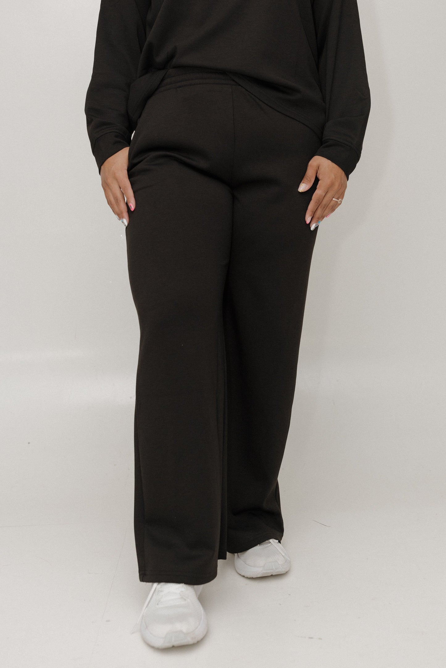 Person wearing a black outfit with wide-leg pants on a white background