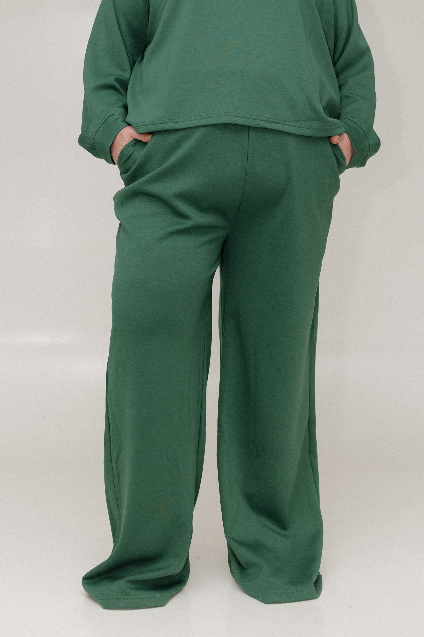 Green sweatshirt and pants set on a white background