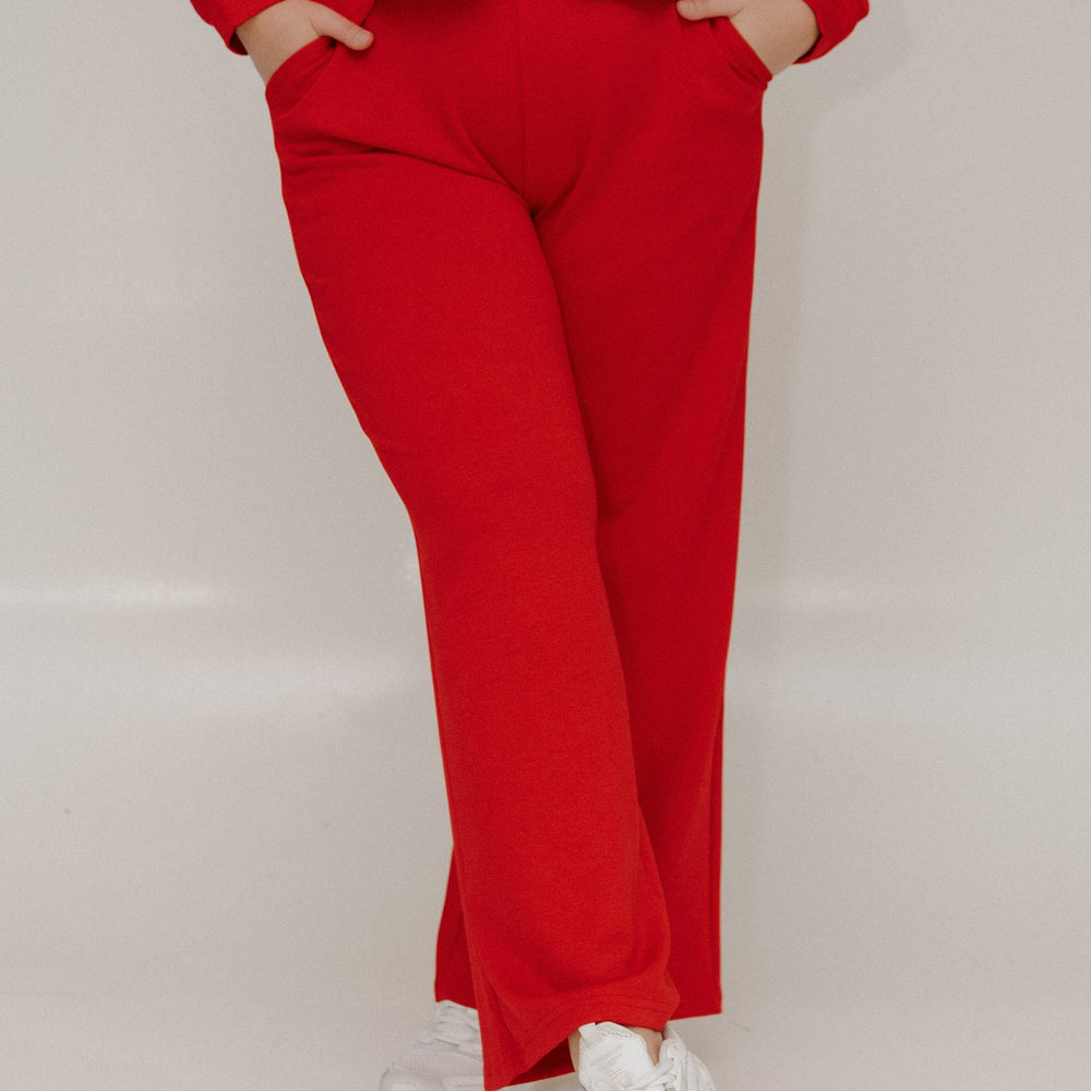 Person wearing a red outfit with white sneakers on a plain background