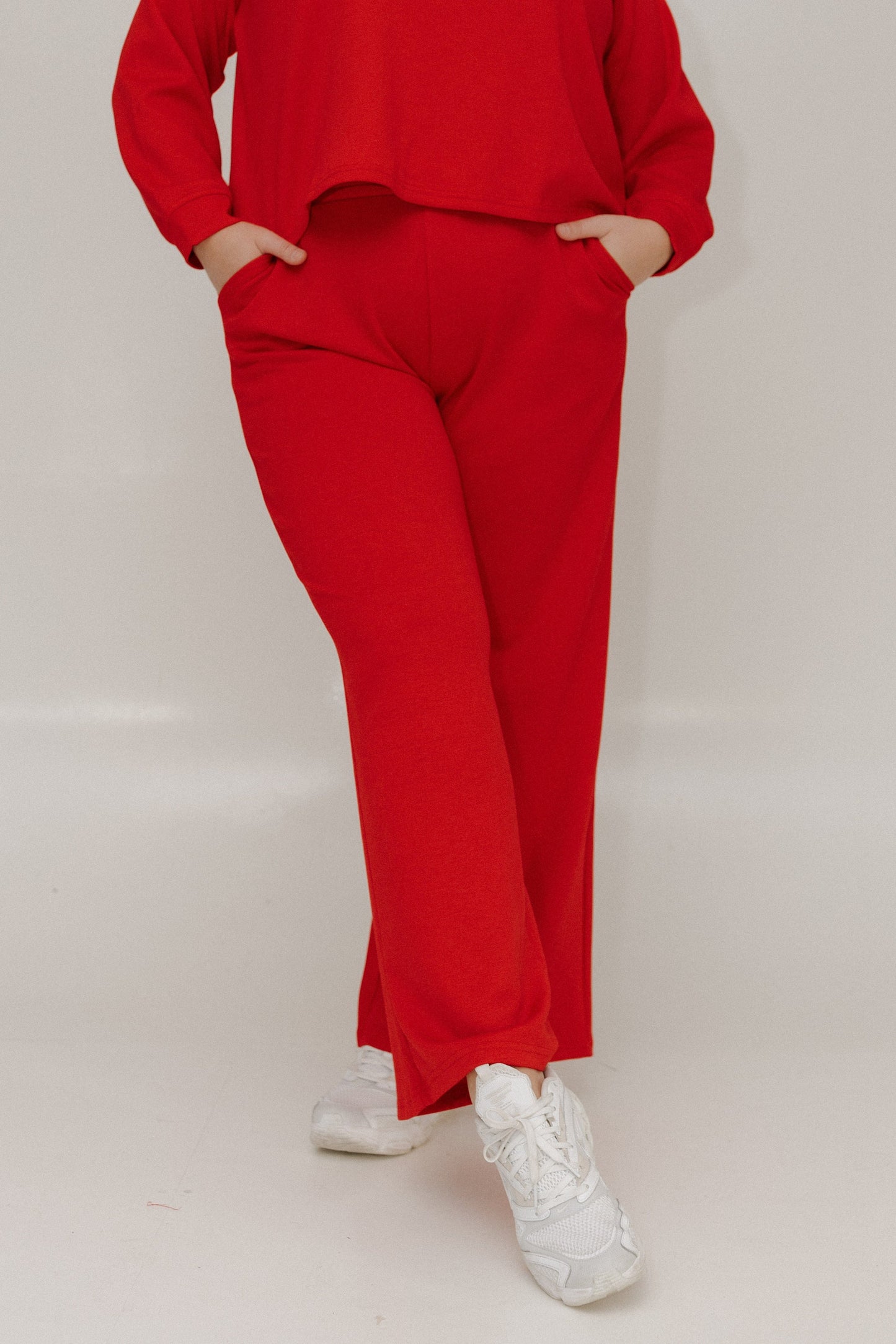 Person wearing a red outfit with white sneakers on a plain background