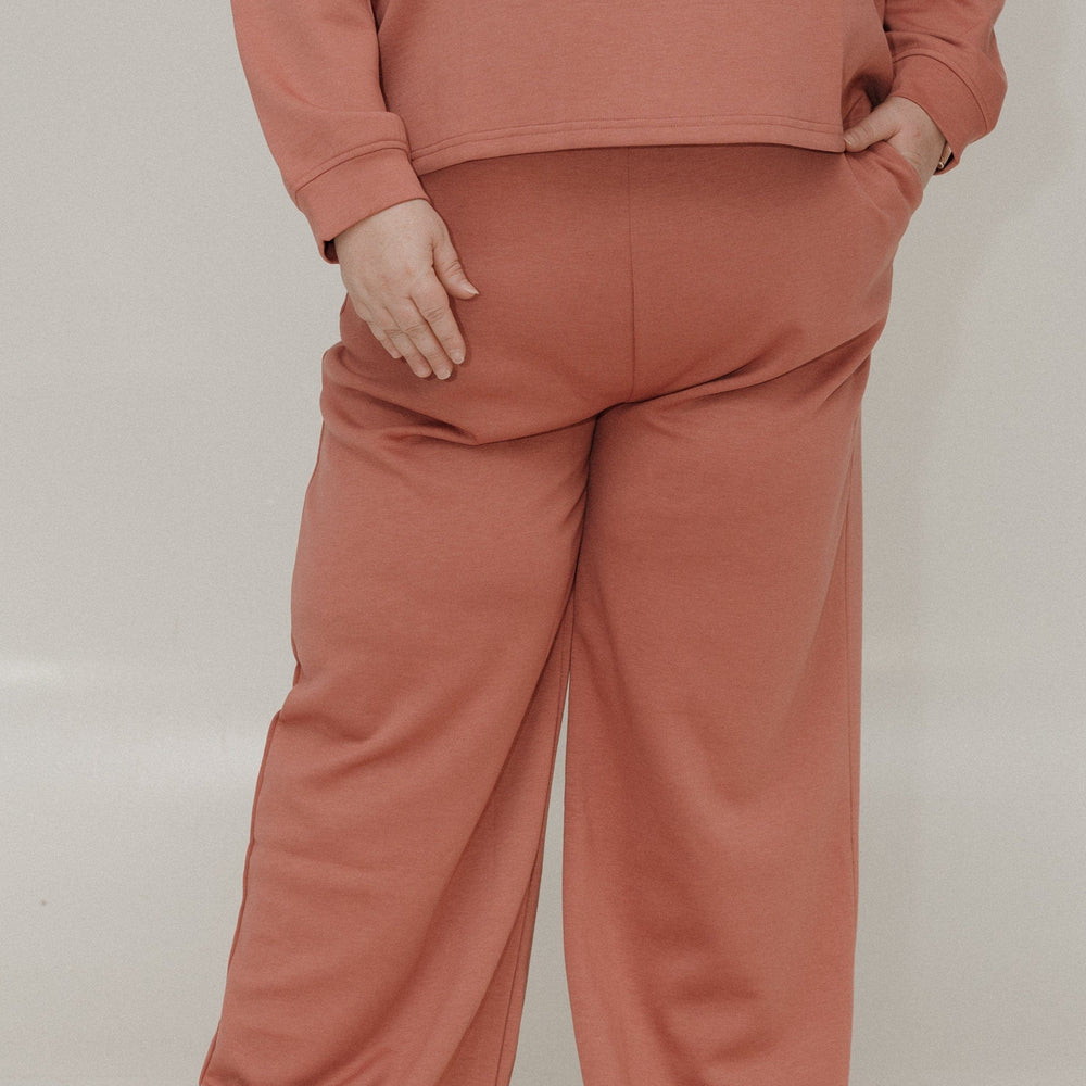 Person wearing a matching pink sweatshirt and pants set on a plain background