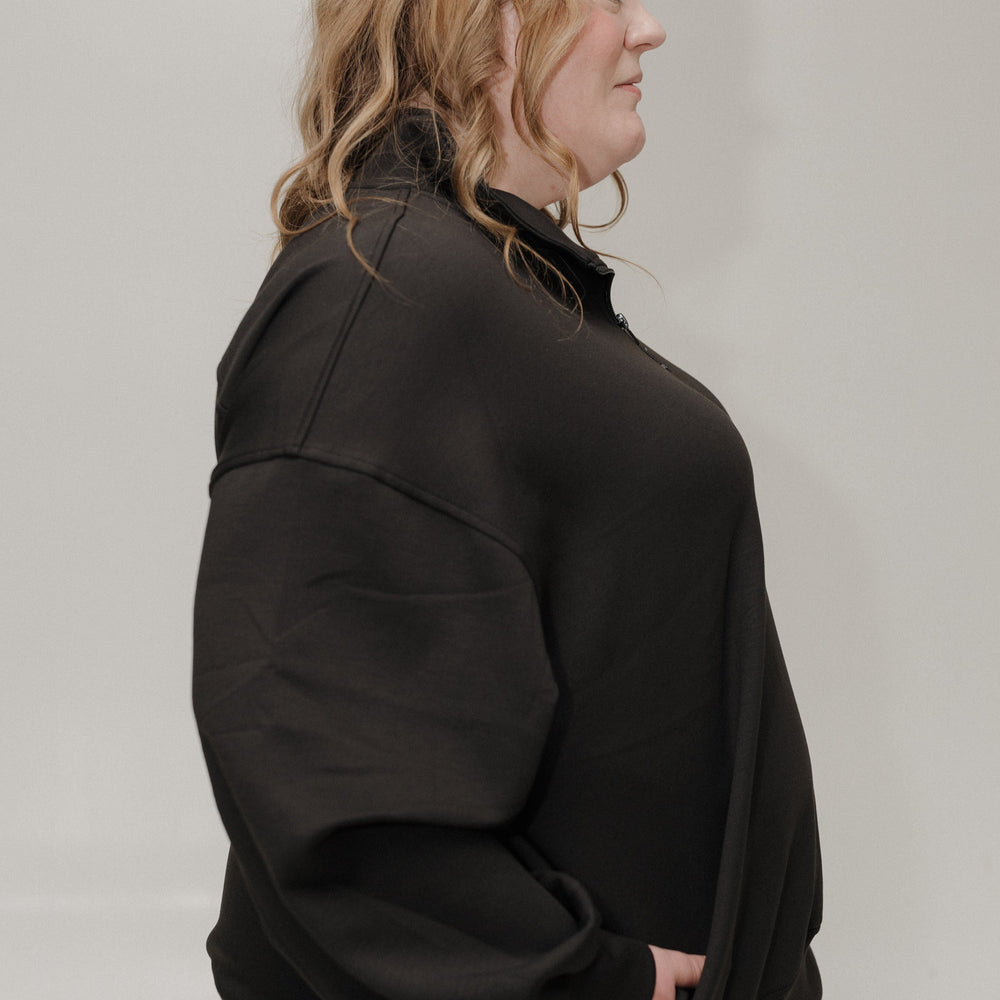 Person wearing a black jacket against a plain background