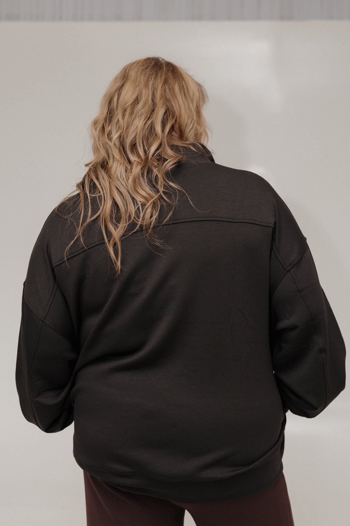 Person wearing a black jacket with a plain background