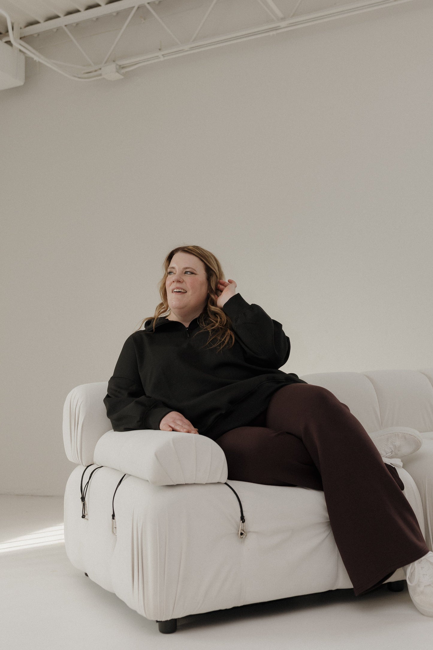 Person sitting on a white armchair in a minimalistic room.