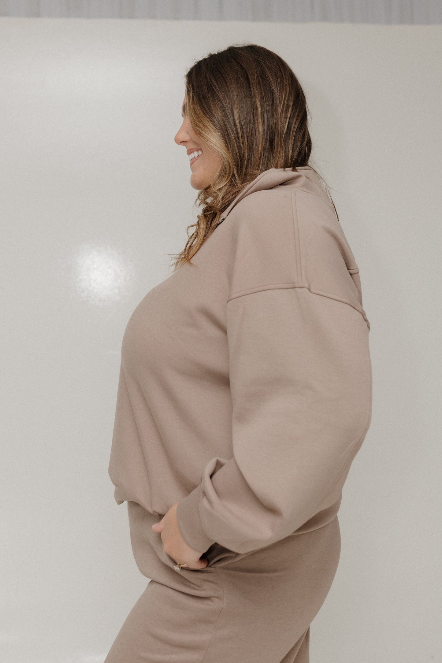 Woman wearing a beige tracksuit against a white background