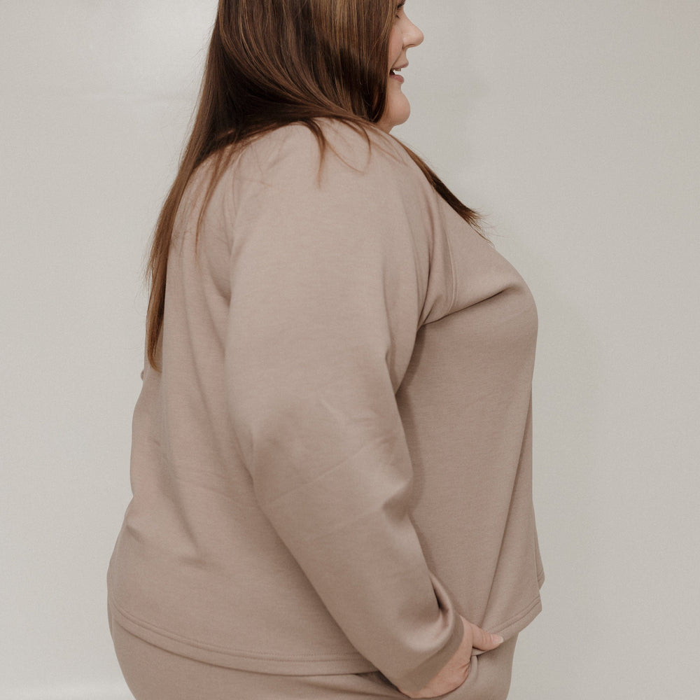 Woman wearing a beige outfit against a plain background