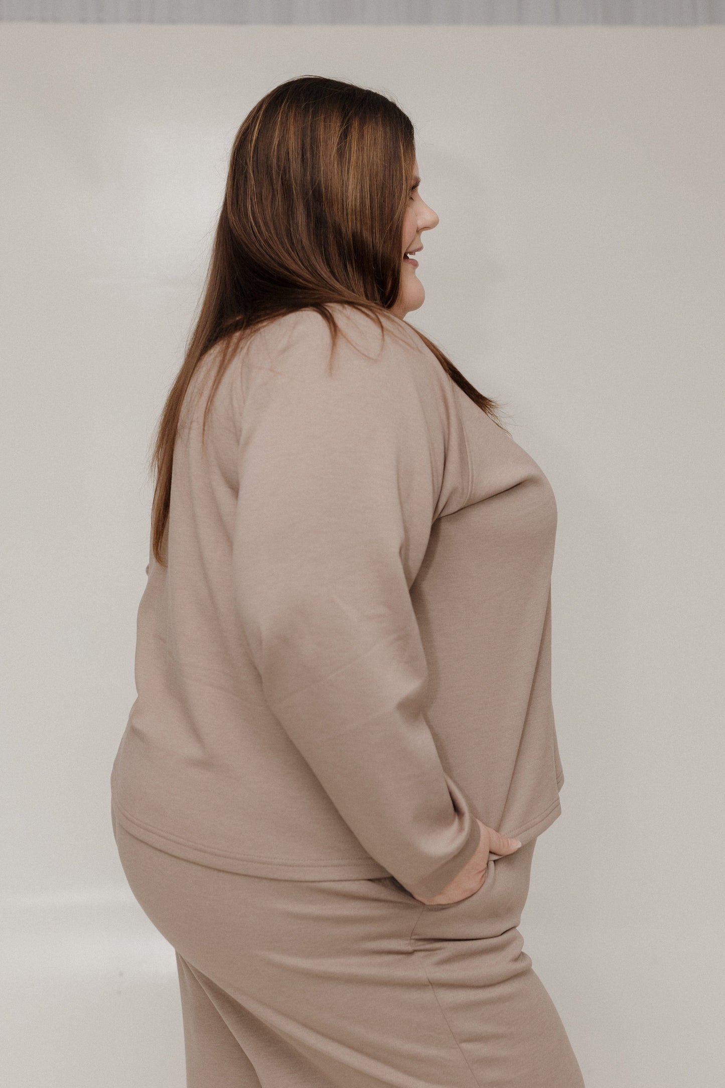 Woman wearing a beige outfit against a plain background