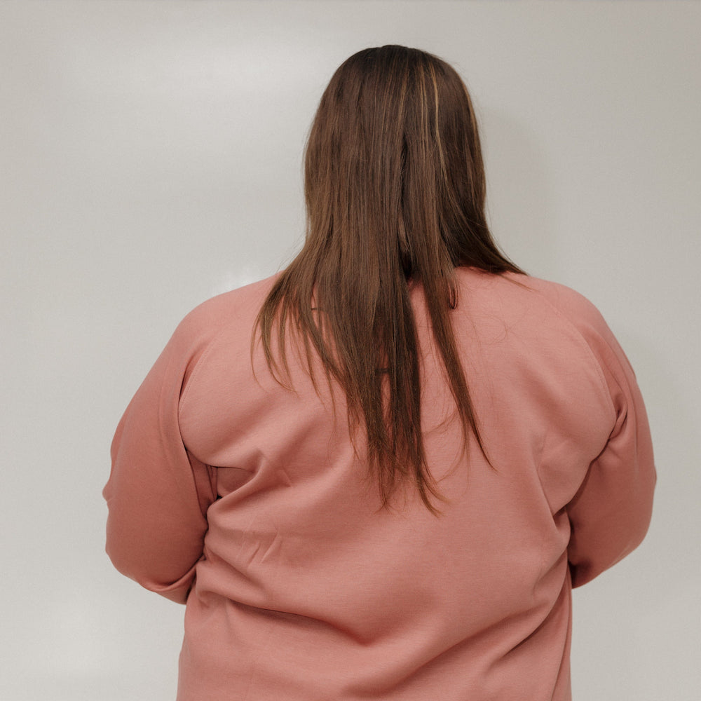 Person wearing a pink outfit standing against a white wall