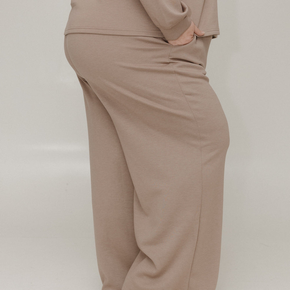 Beige outfit with a top and wide-leg pants on a plain background