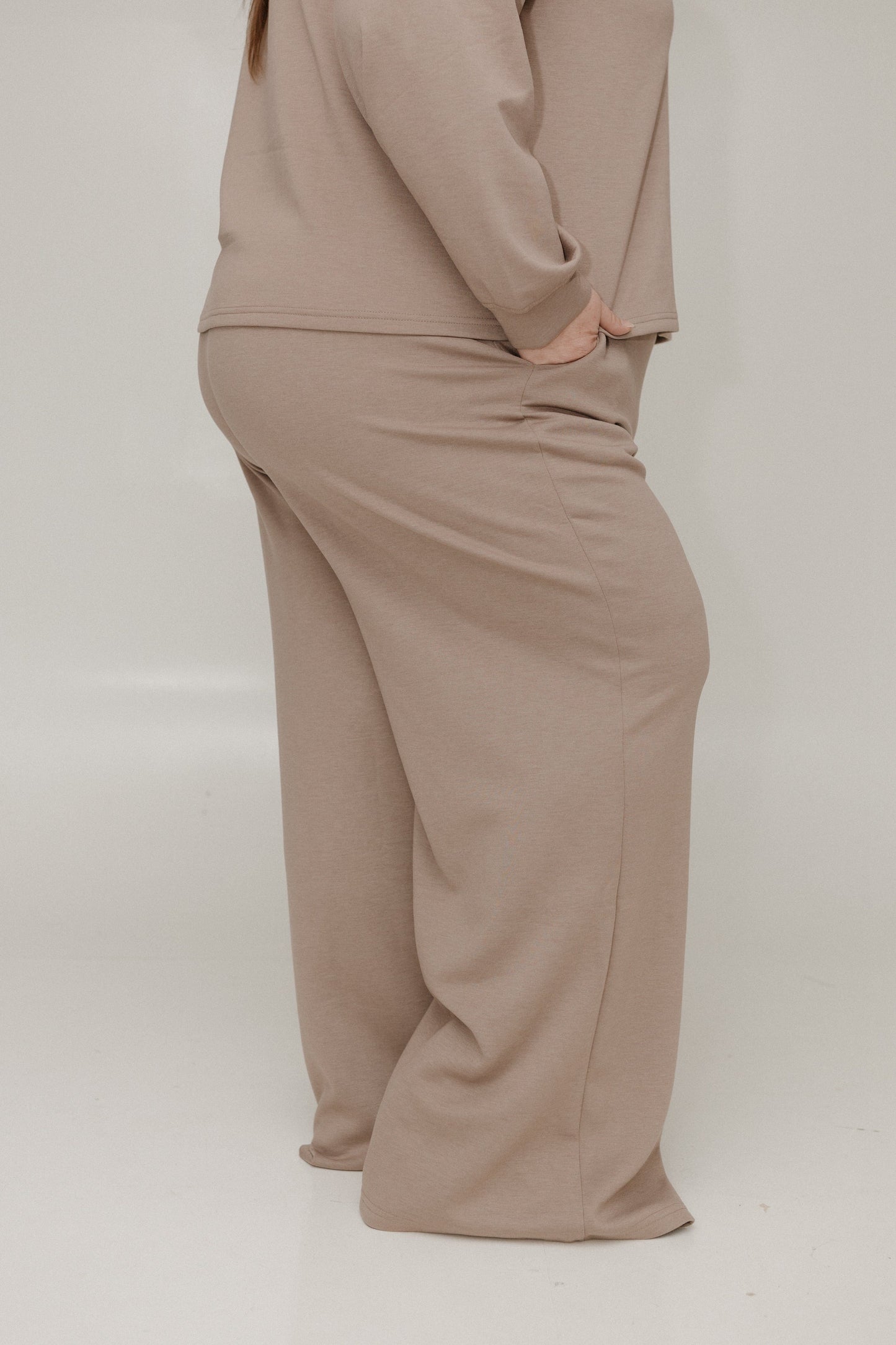 Beige outfit with a top and wide-leg pants on a plain background